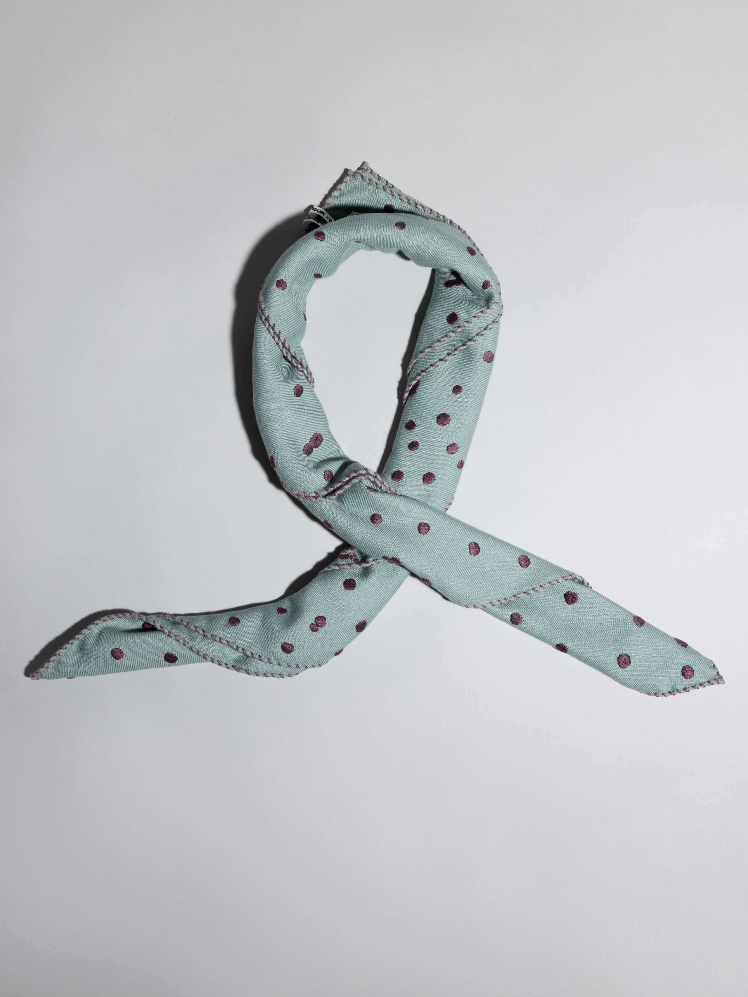folded Leo wool scarf with dots in a light bluish rosemary green an purple embroidery