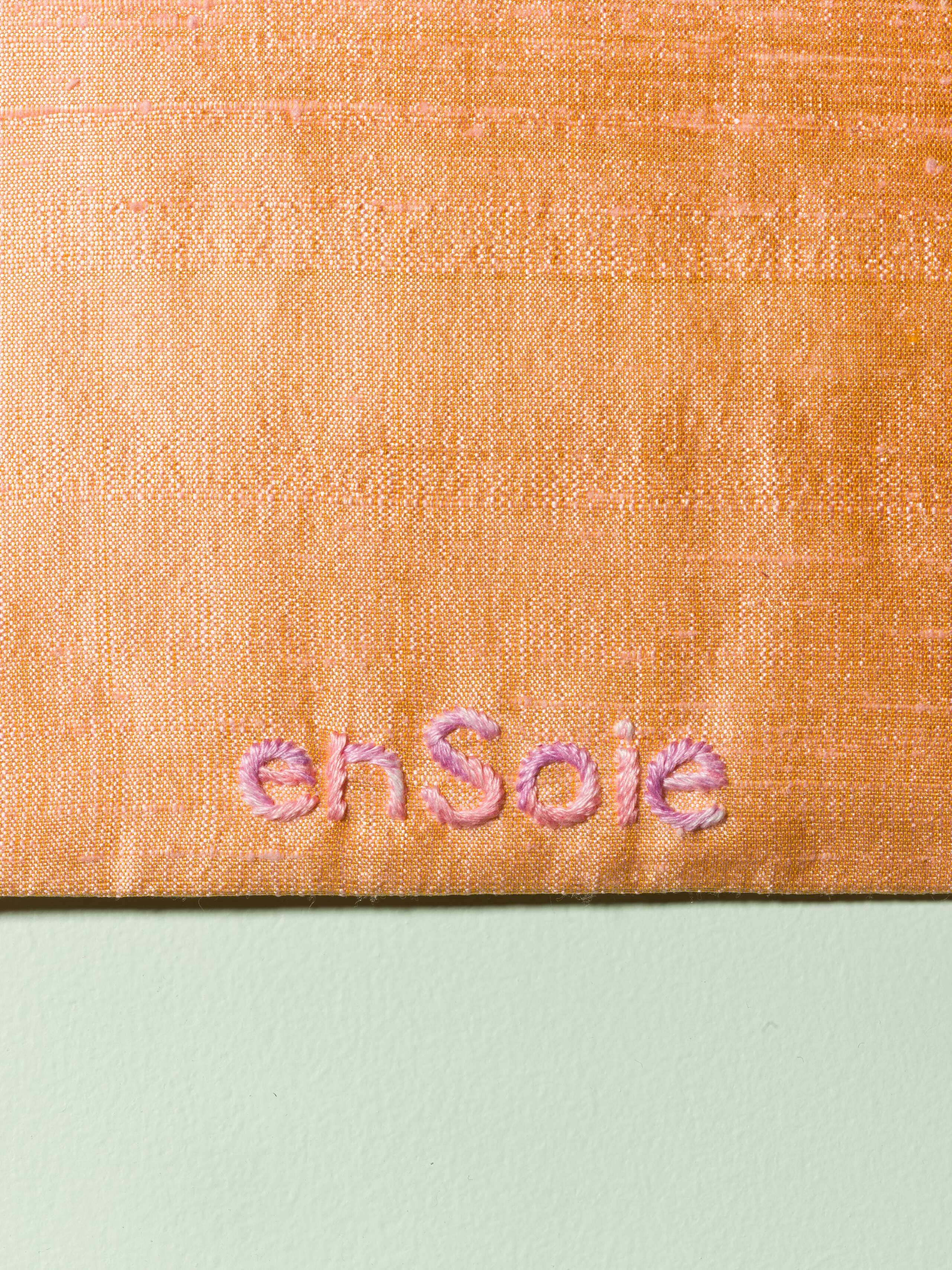 Detail of beautiful silk clutch in a pale orange with a pearly gloss and beautiful embroidery enSoie in pink