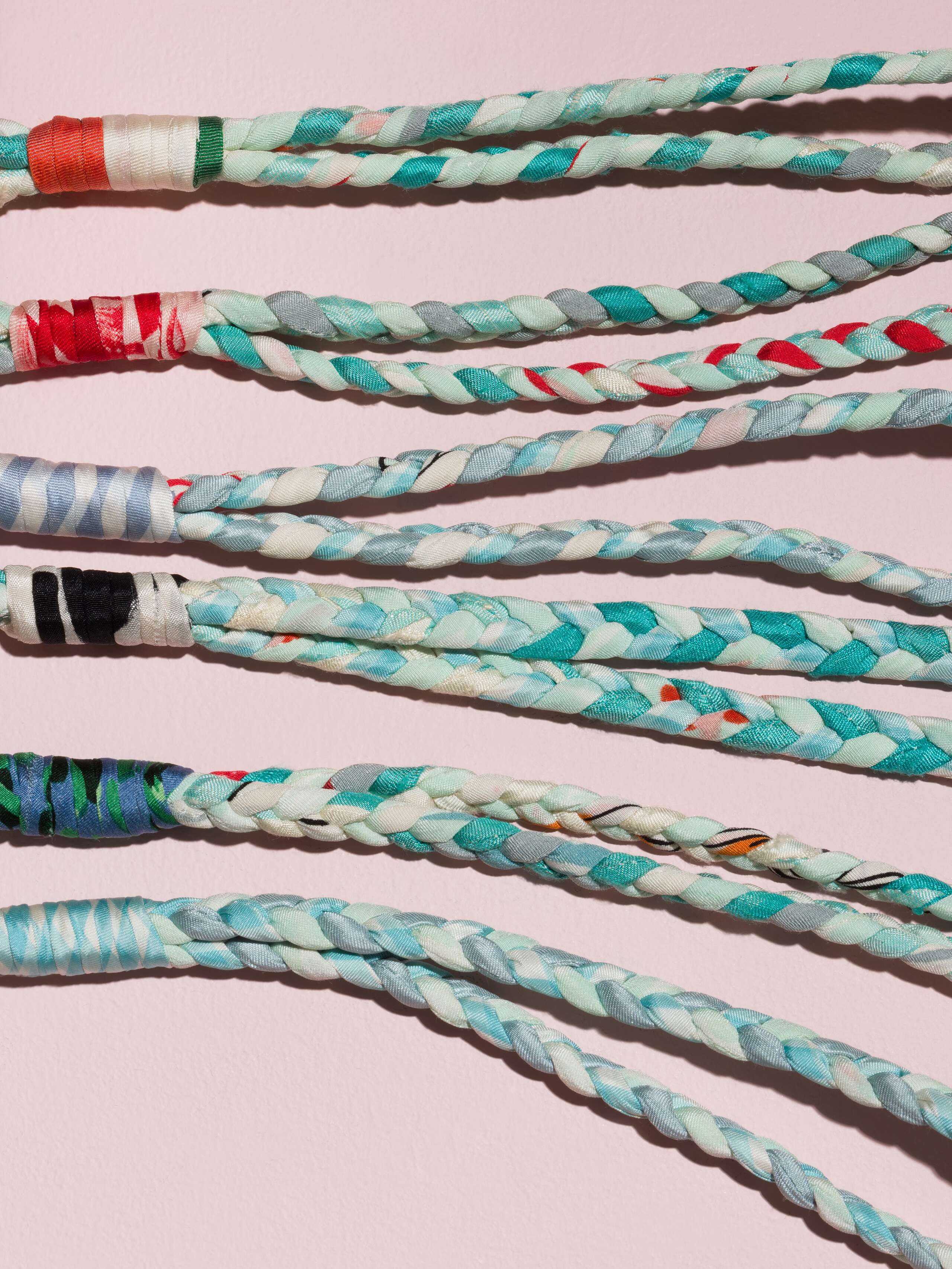 details of four braided keychains in light blue shades in silk
