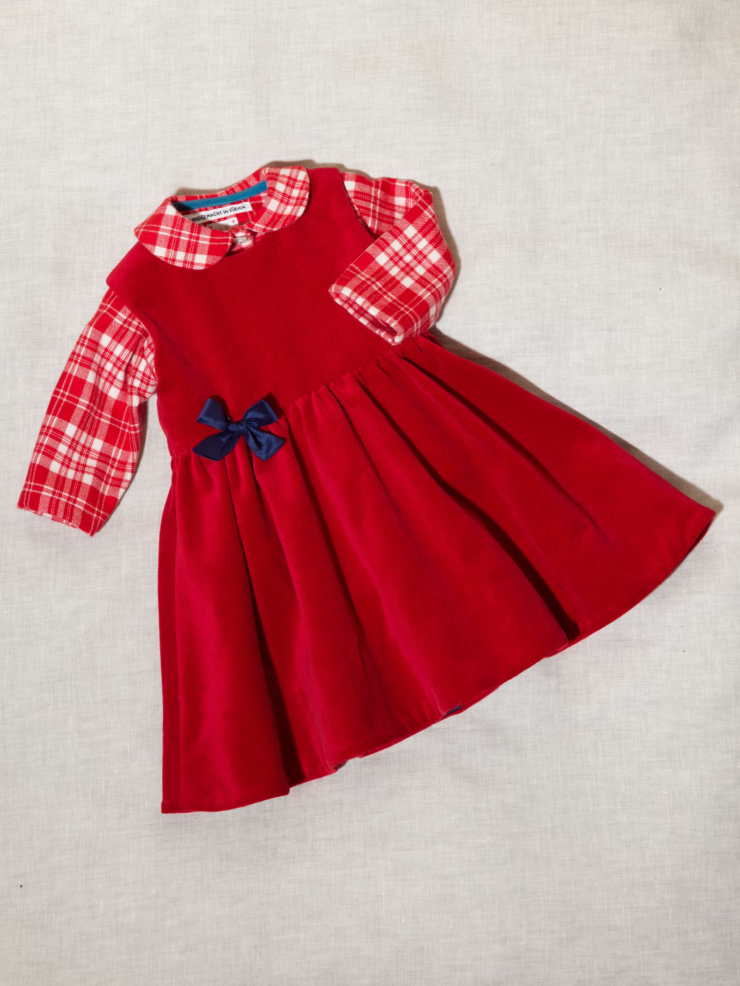 Detail of beautiful cotton velvet baby dress sleeveless with navy silk bow handmade in Zurich, red cotton velvet and flannel red check baby bodysuit