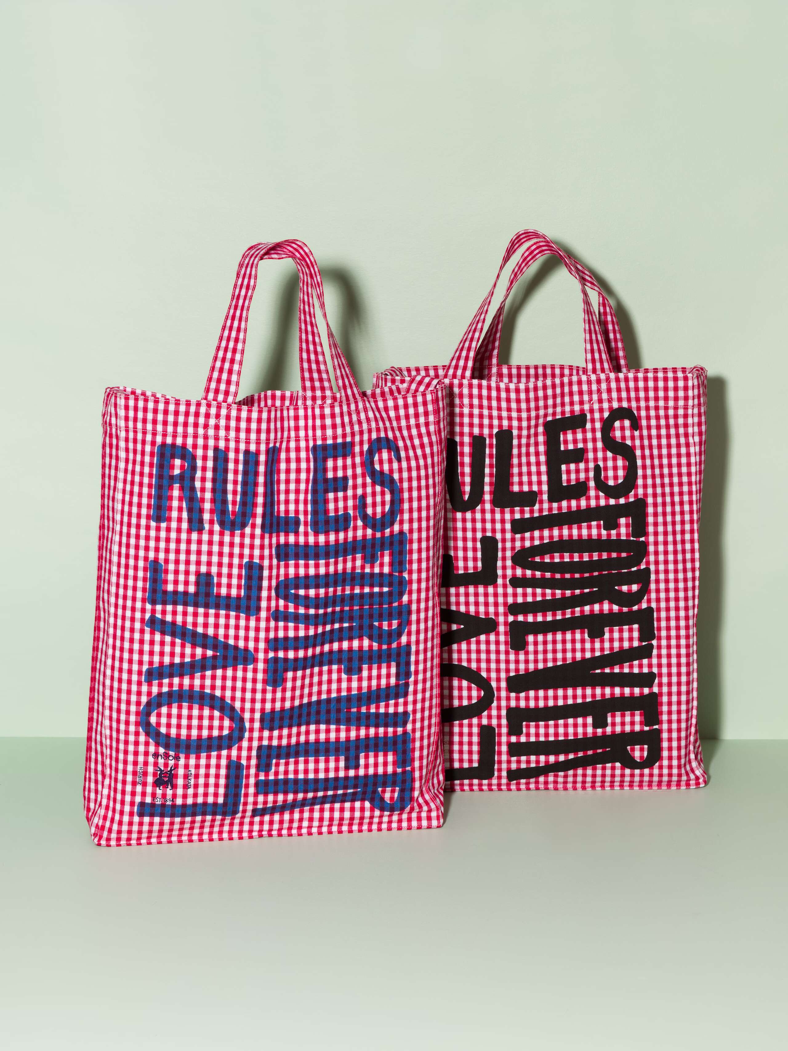 Two cotton tote bags with a red vichy pattern and a navy and black print that says "Love rules forever"