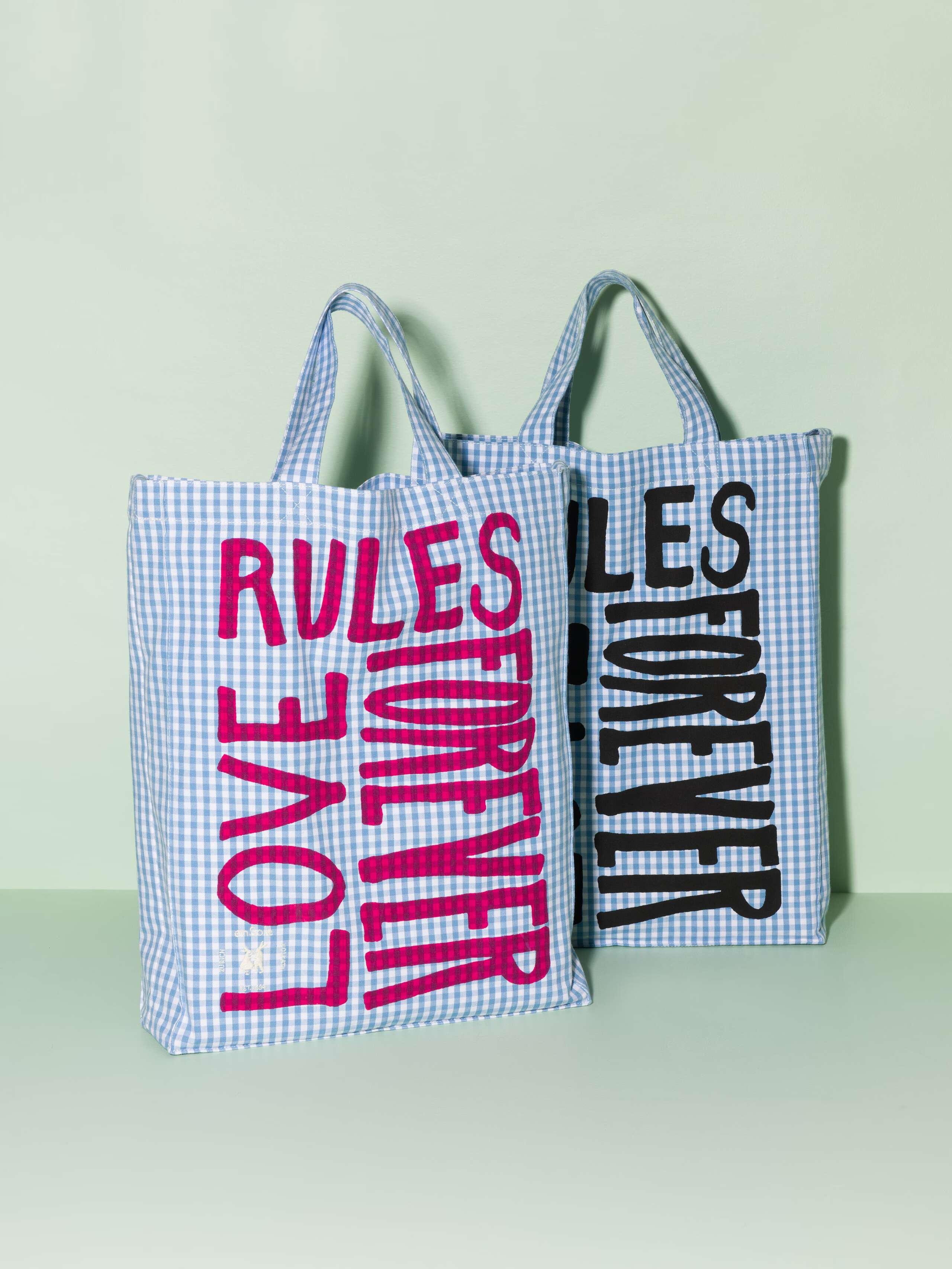 Two cotton tote bags with a light blue vichy pattern and a pink and black print that says "Love rules forever"