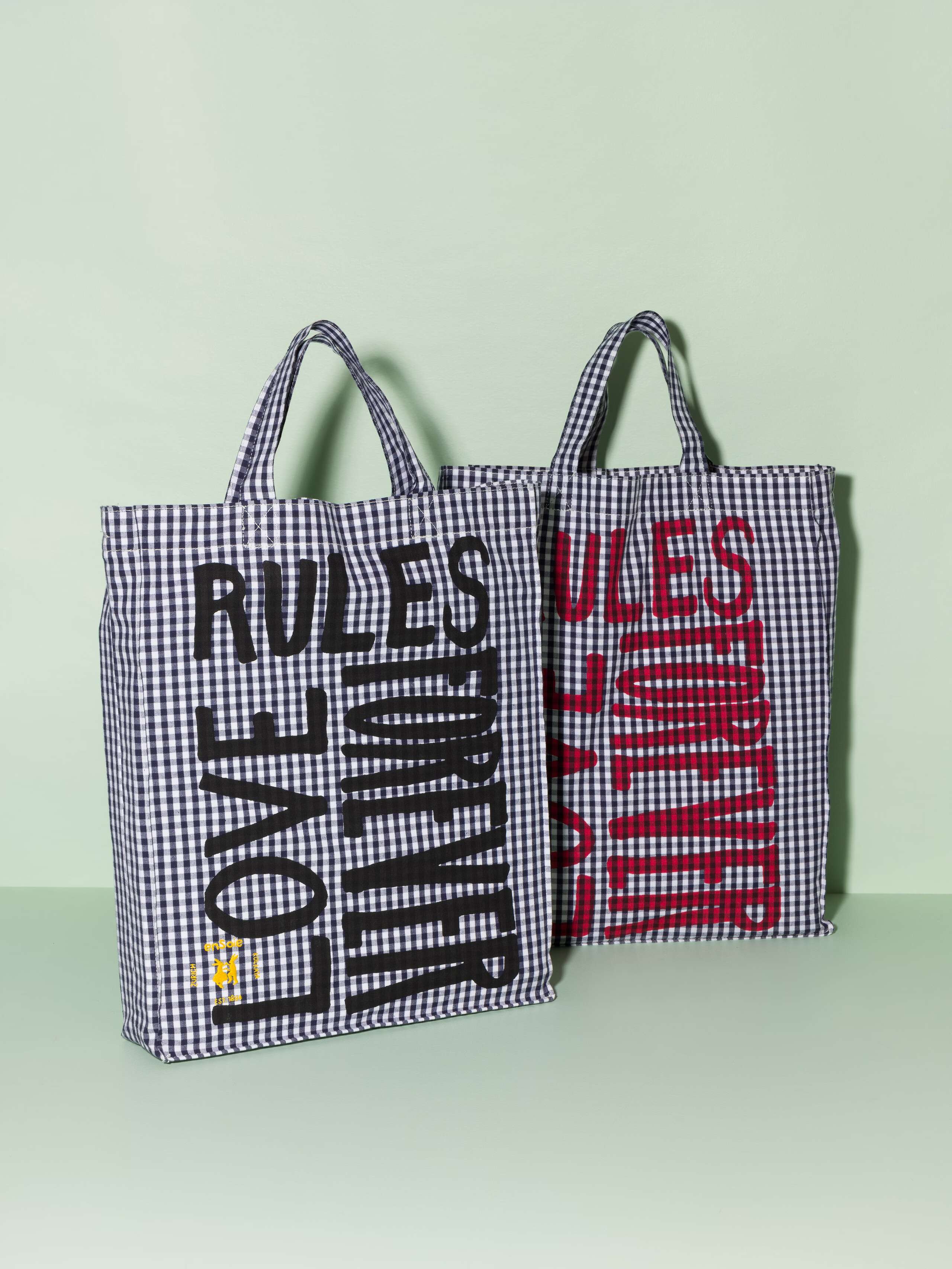 Two cotton tote bags with a navy vichy pattern and a black and red print that says "Love rules forever"