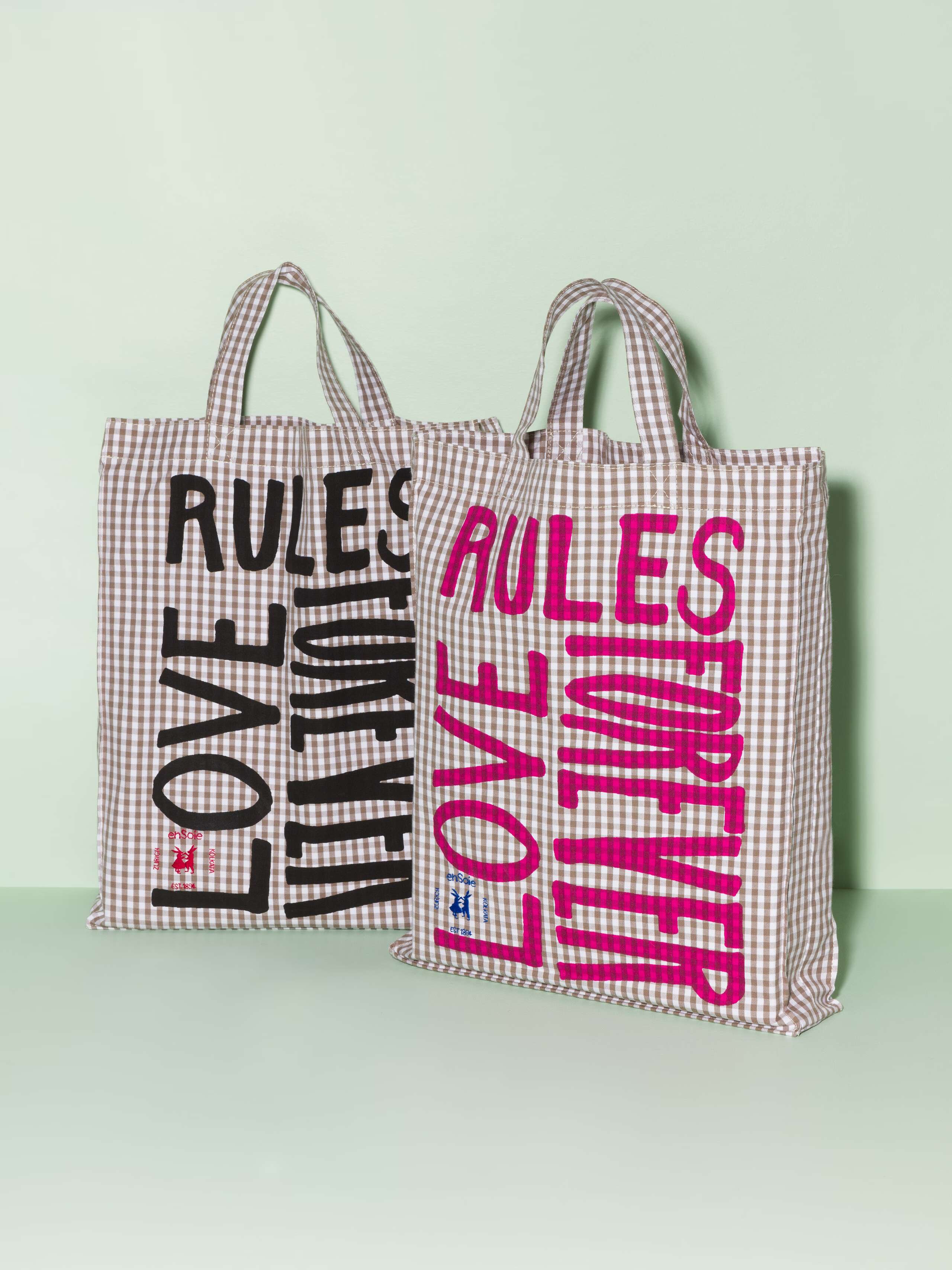 Two cotton tote bags with a beige vichy pattern and a black and pink print that says "Love rules forever"