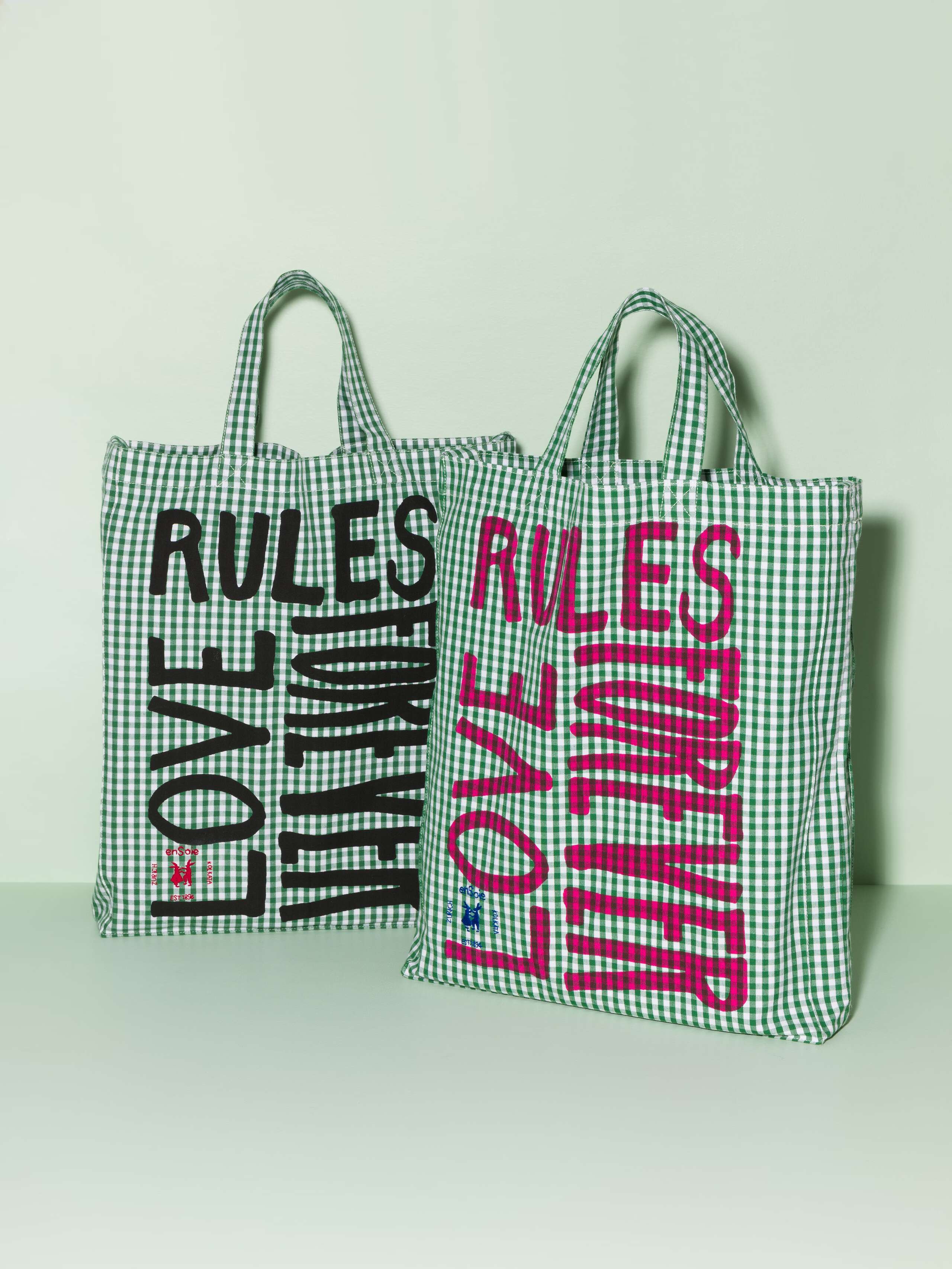 Two cotton tote bags with a green vichy pattern and a pink and black print that says "Love rules forever"