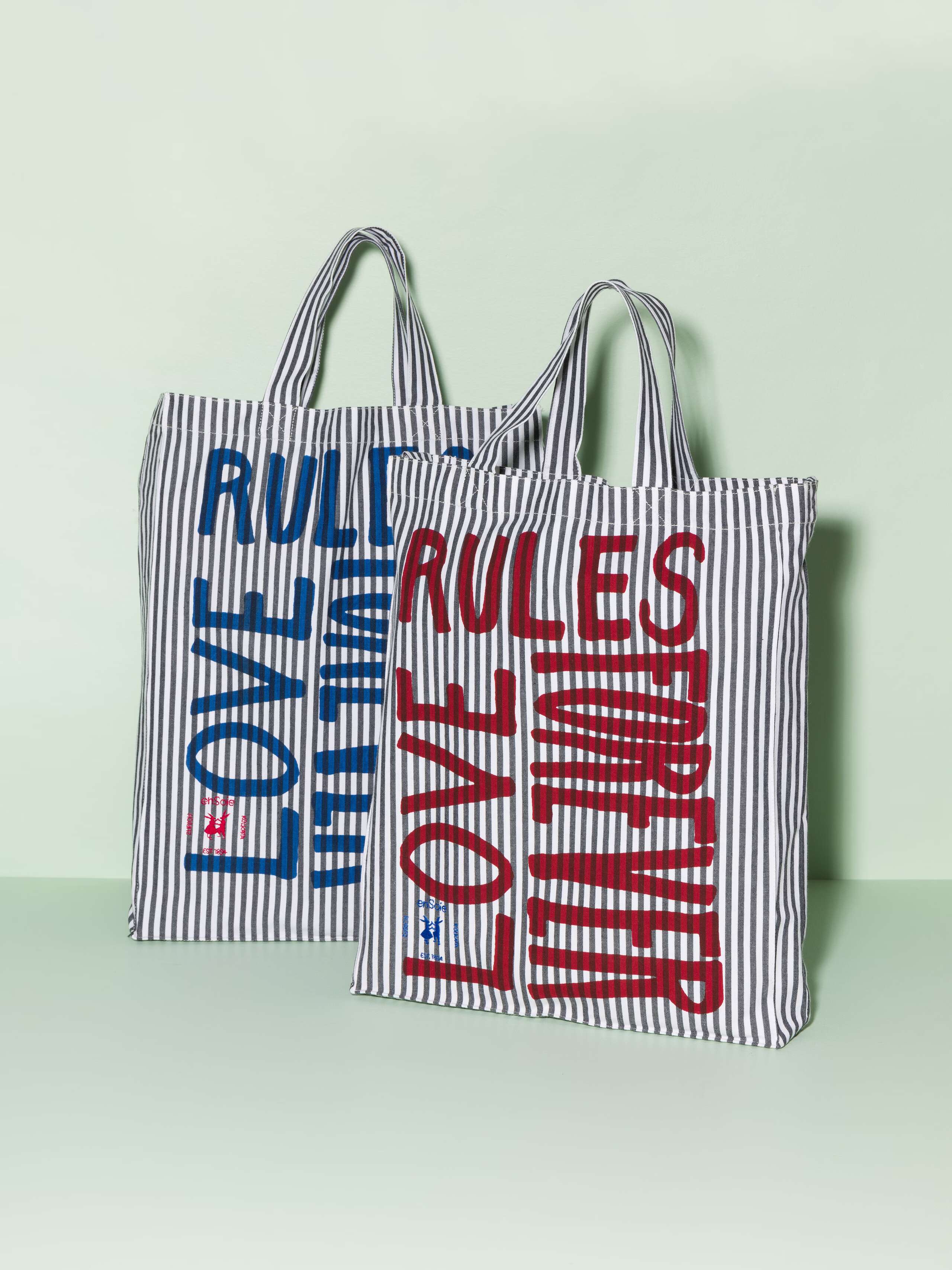 Two cotton tote bags with a black stripe pattern and a navy and red print that says "Love rules forever"