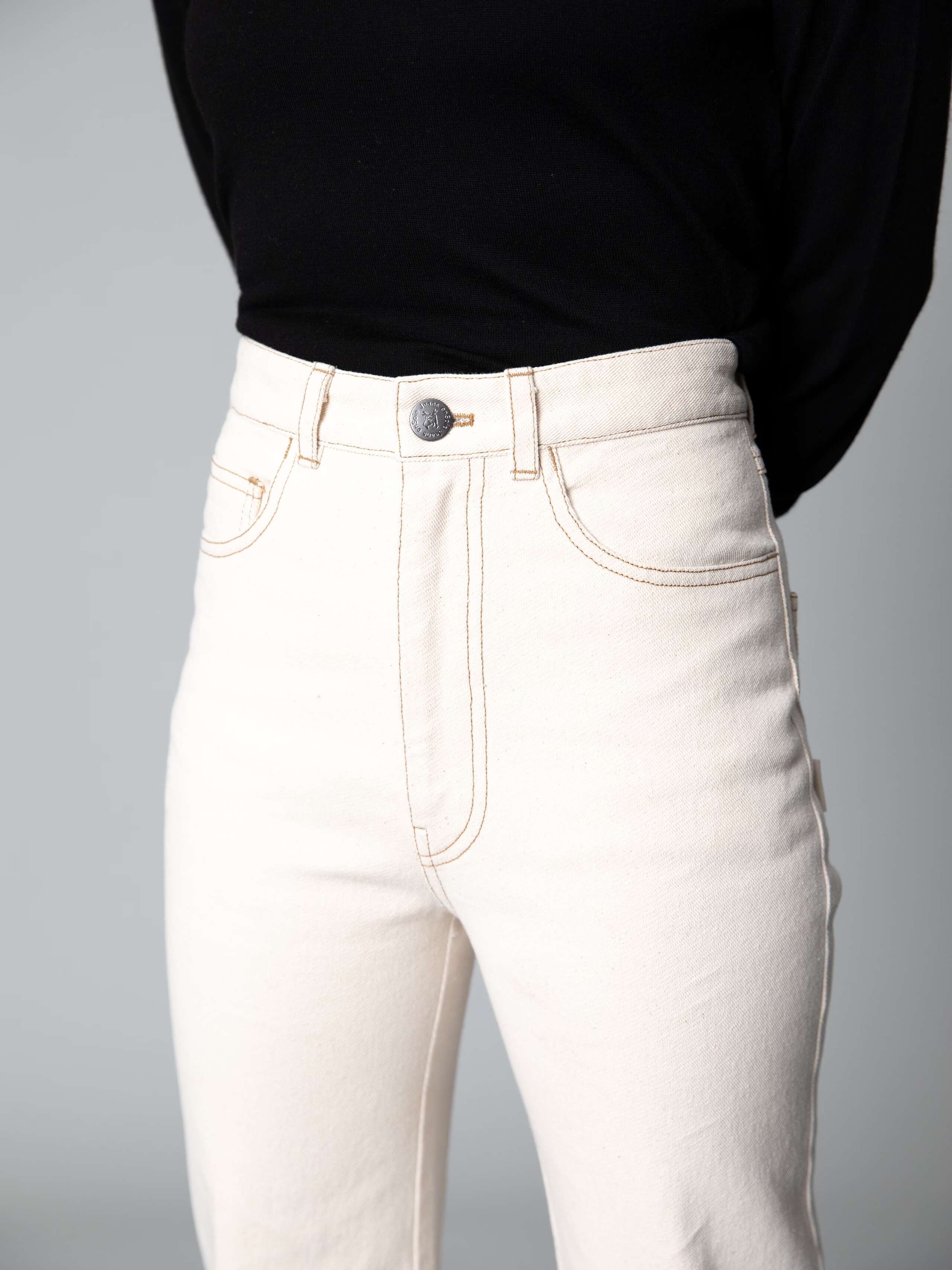 Detail of a beautiful high waist jeans in ecru  featuring a straight cut 