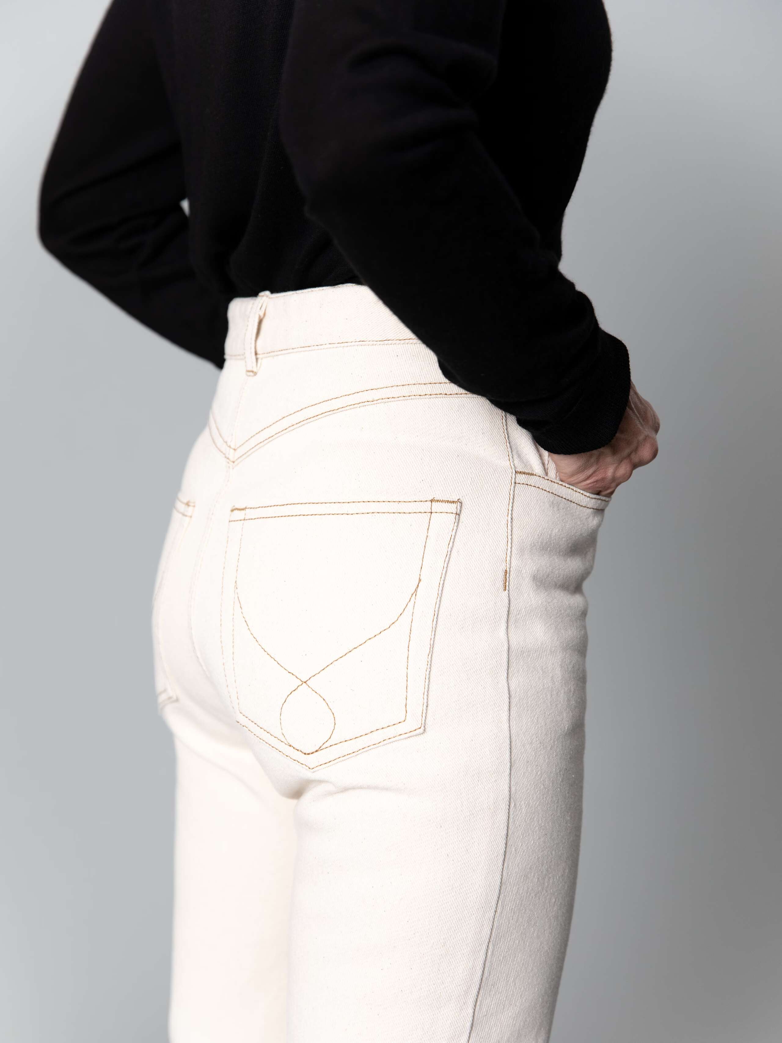 Detail of a beautiful high waist jeans in ecru  featuring a straight cut 