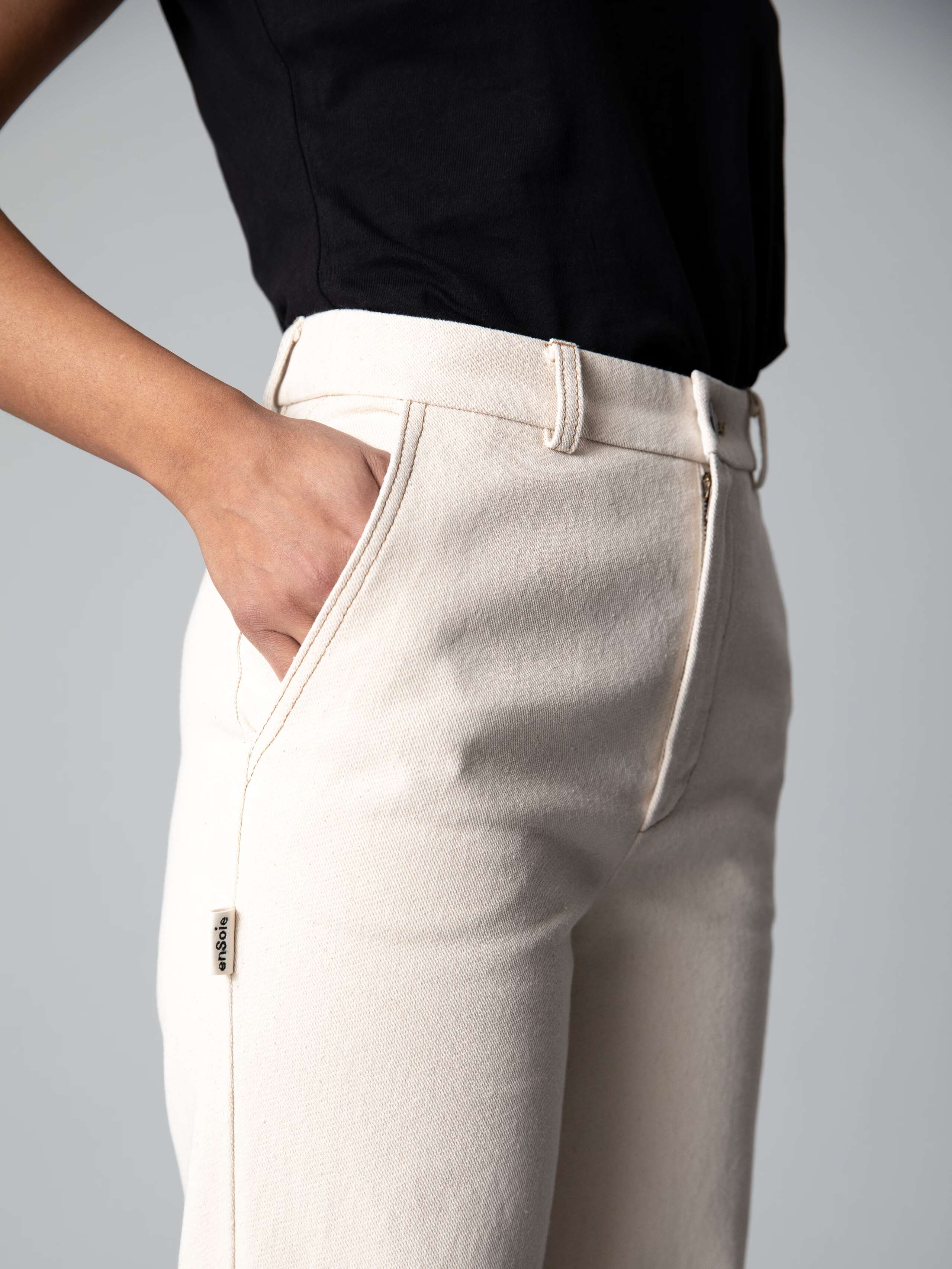 Detail of a cotton denim jeans in an ecru colour shade combined with a white shirt and black ballerina flats 