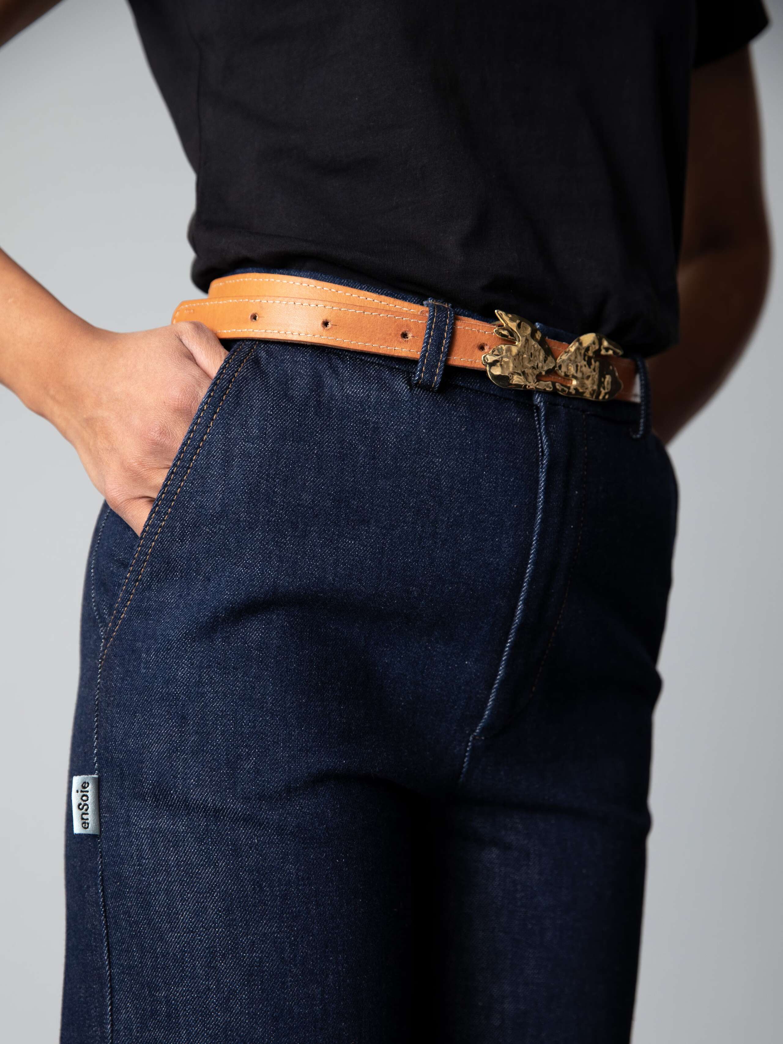 Detail of a high waisted wide leg jeans in a classy indigo colour combined with a white shirt and black ballerina flats 