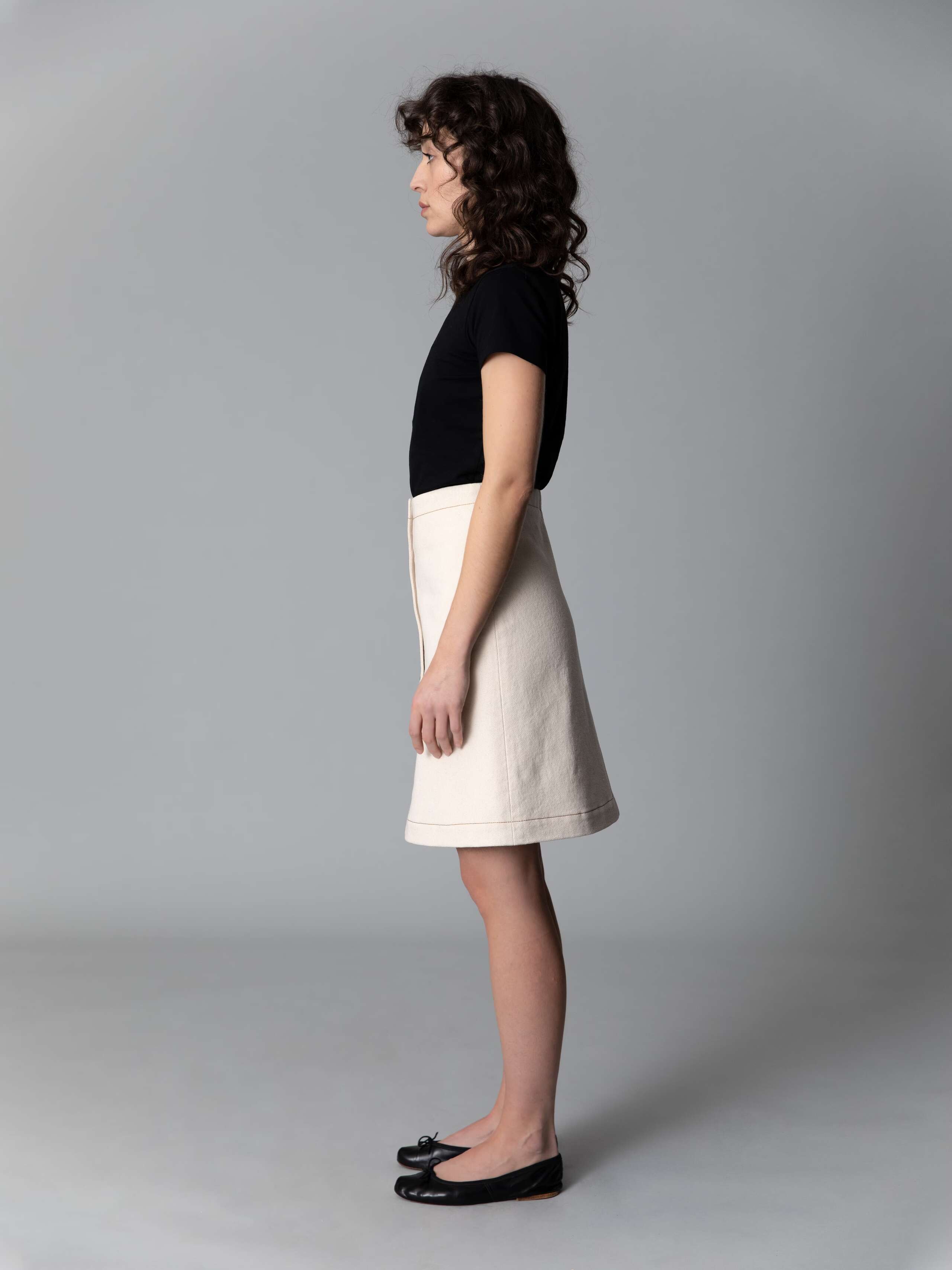 Model wears a beautiful a-line denim skirt in an ecru colour shade combined with black ballerina flats and a black t-shirt