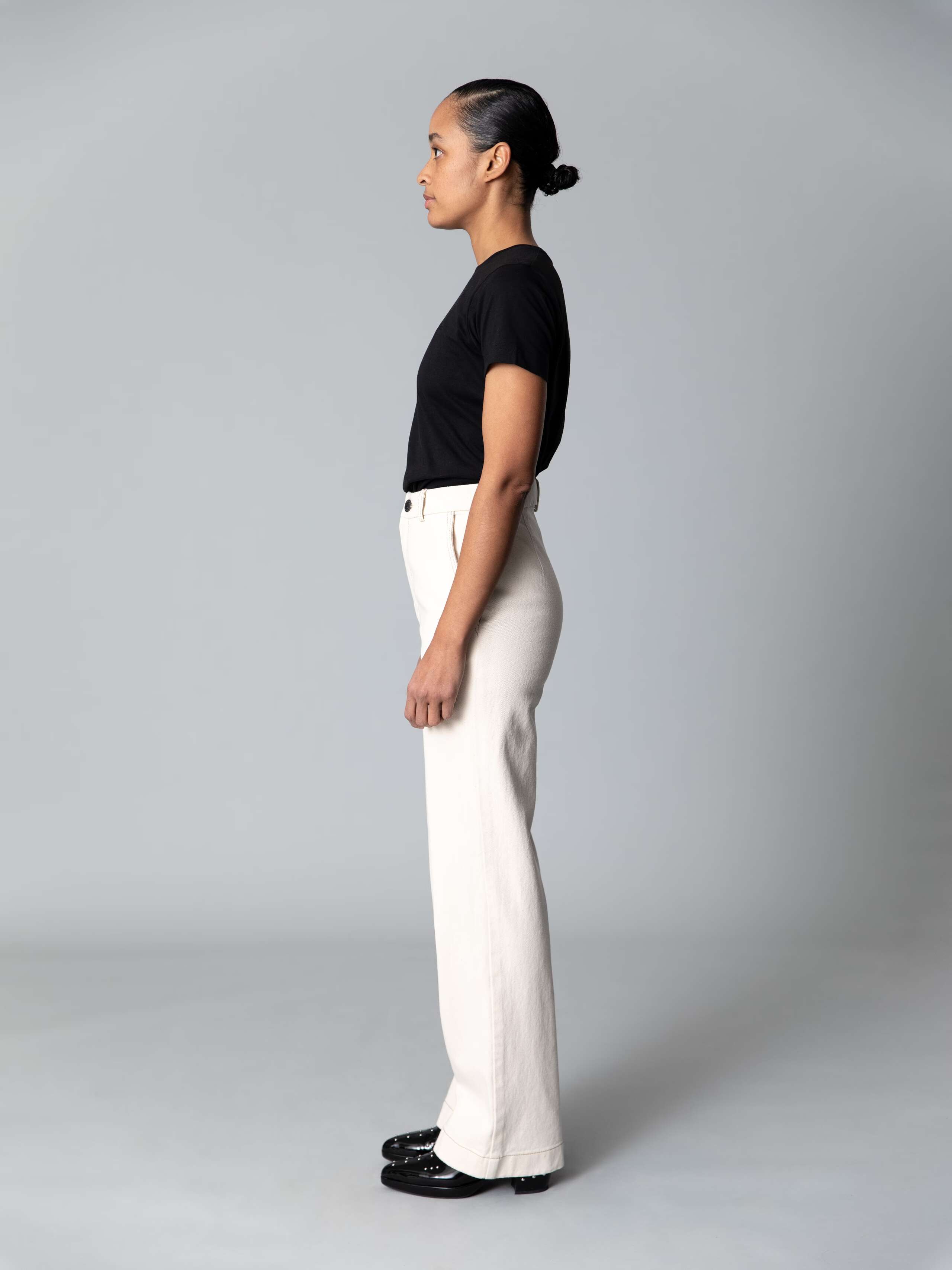 Model is weraing a cotton denim jeans in an ecru colour shade combined with a white shirt and black ballerina flats 