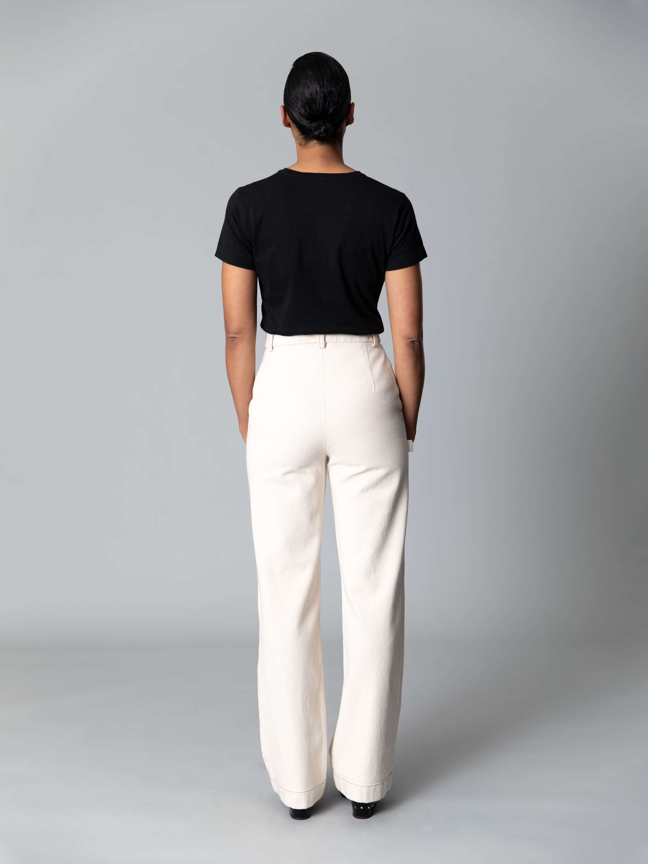 Model is weraing a cotton denim jeans in an ecru colour shade combined with a white shirt and black ballerina flats 