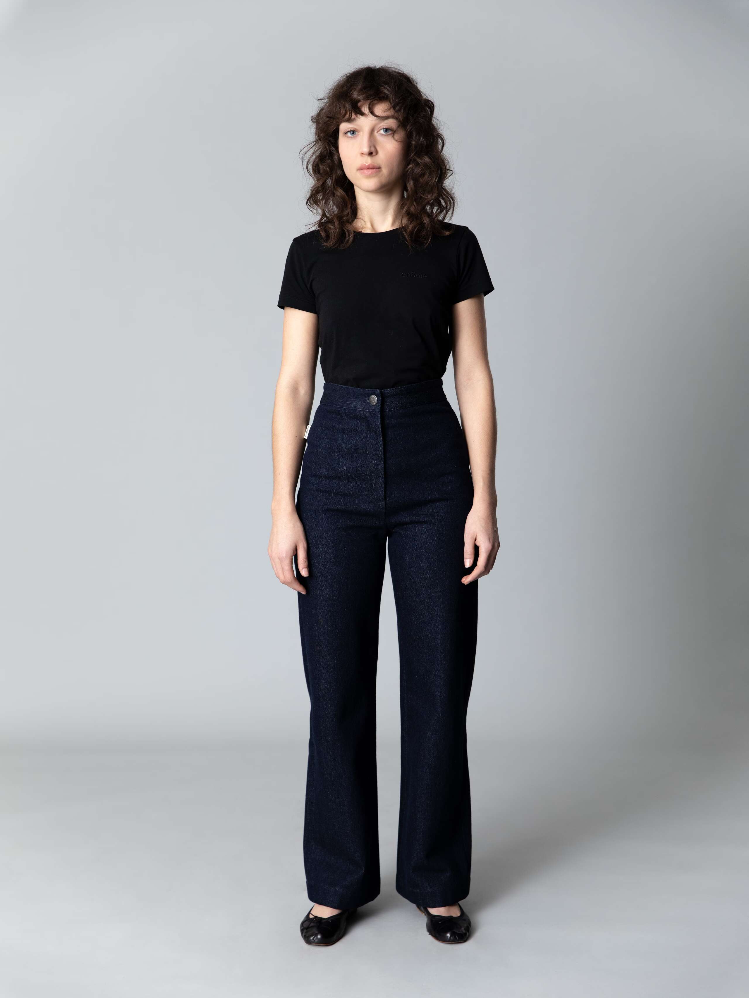 Model wears beautiful wide leg and high waist denim trousers and a black cotton shirt