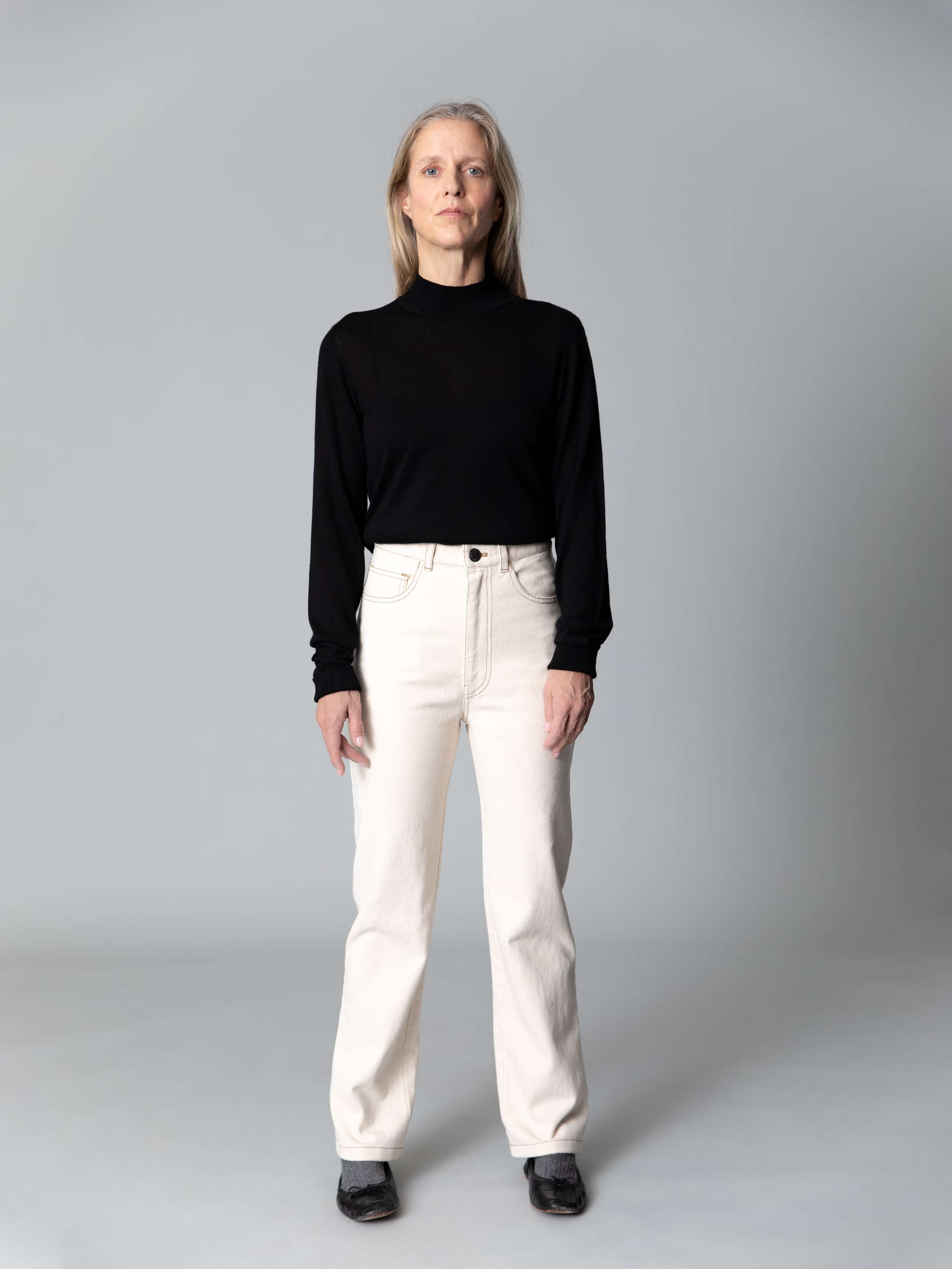 Model wearing nice jeans in ecru colour shades combined with a black turtleneck and black ballerina flats