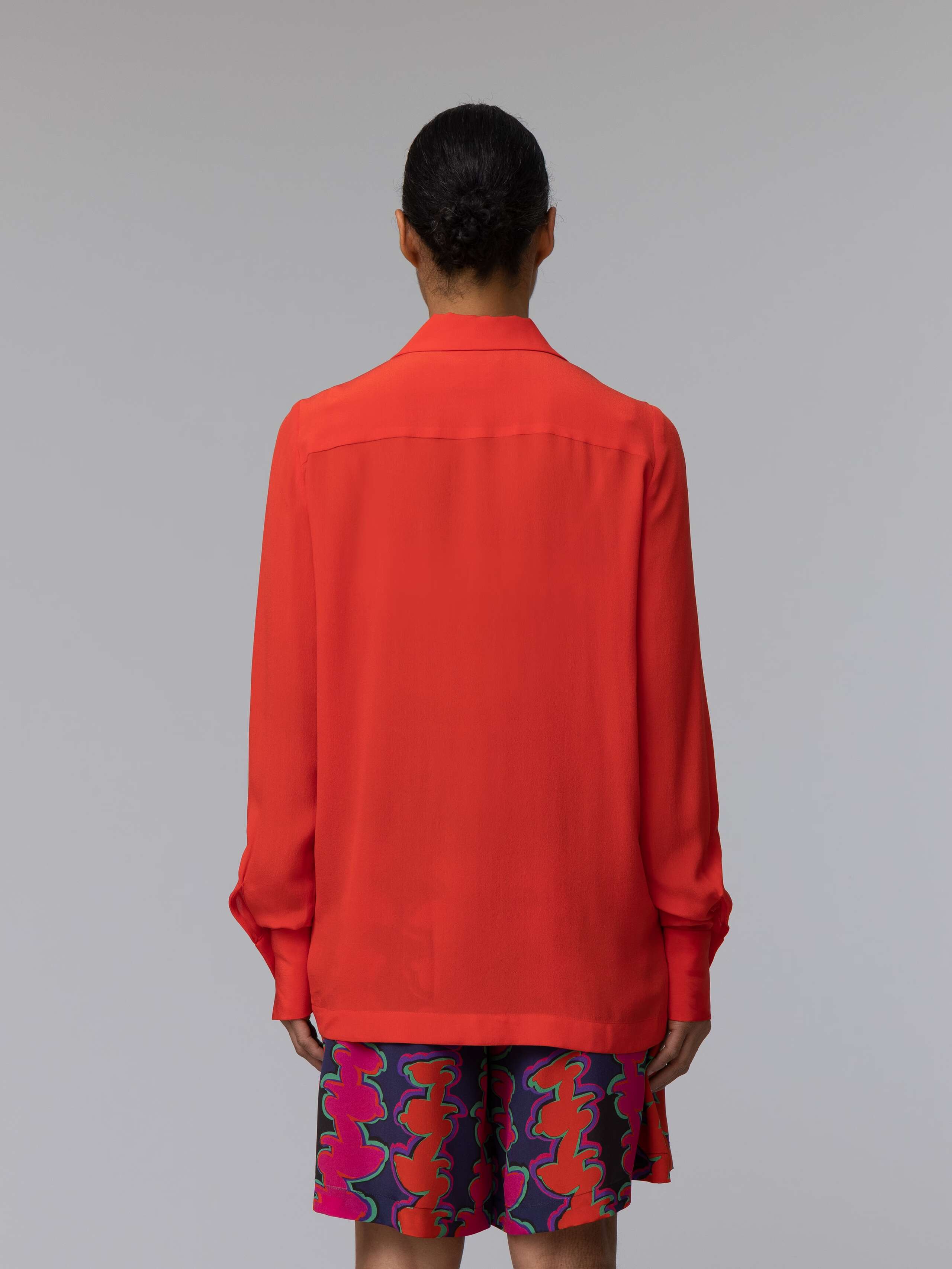 Model wears a long bright red silk blouse 