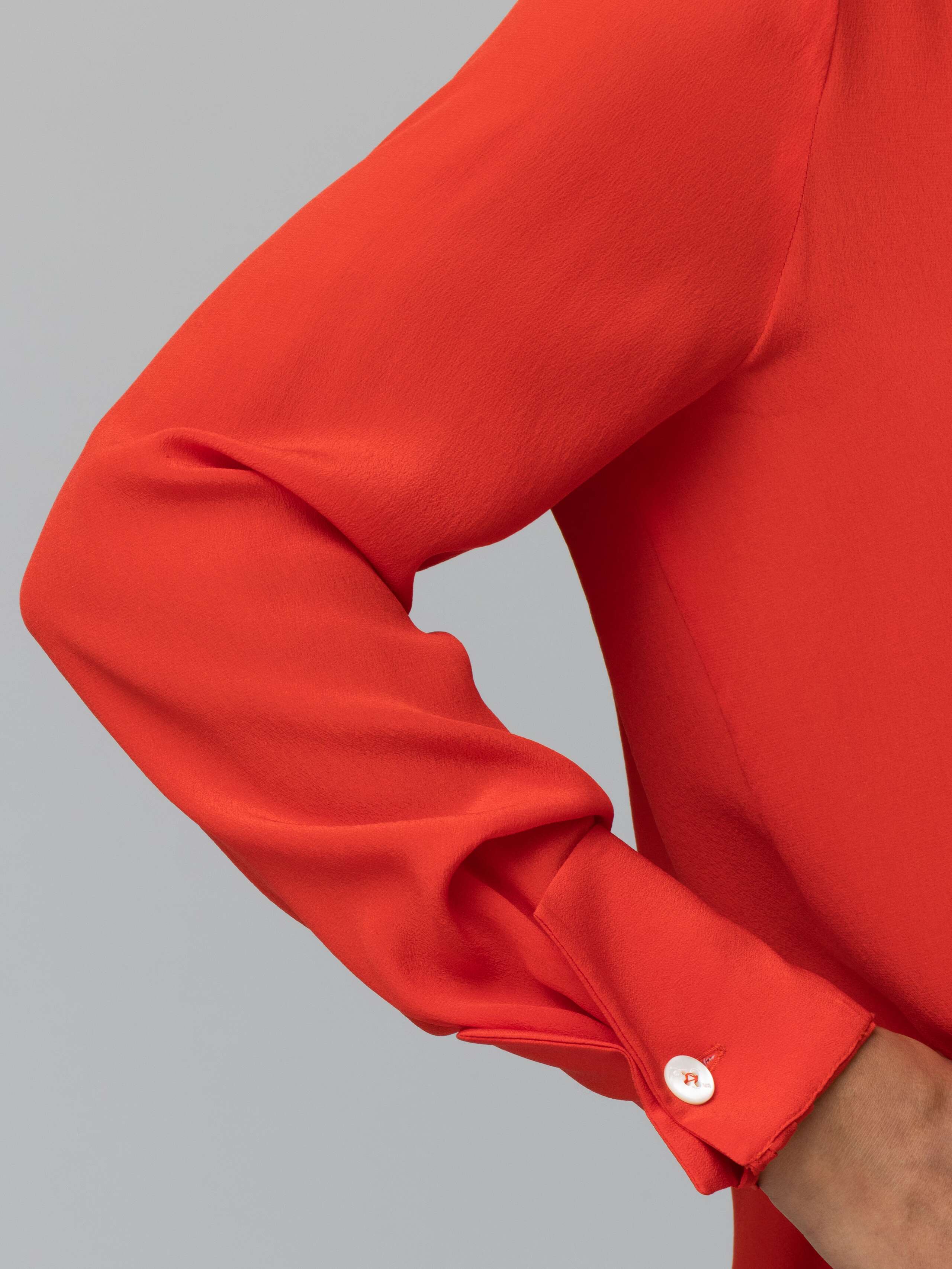 detail of a long bright red silk blouse 