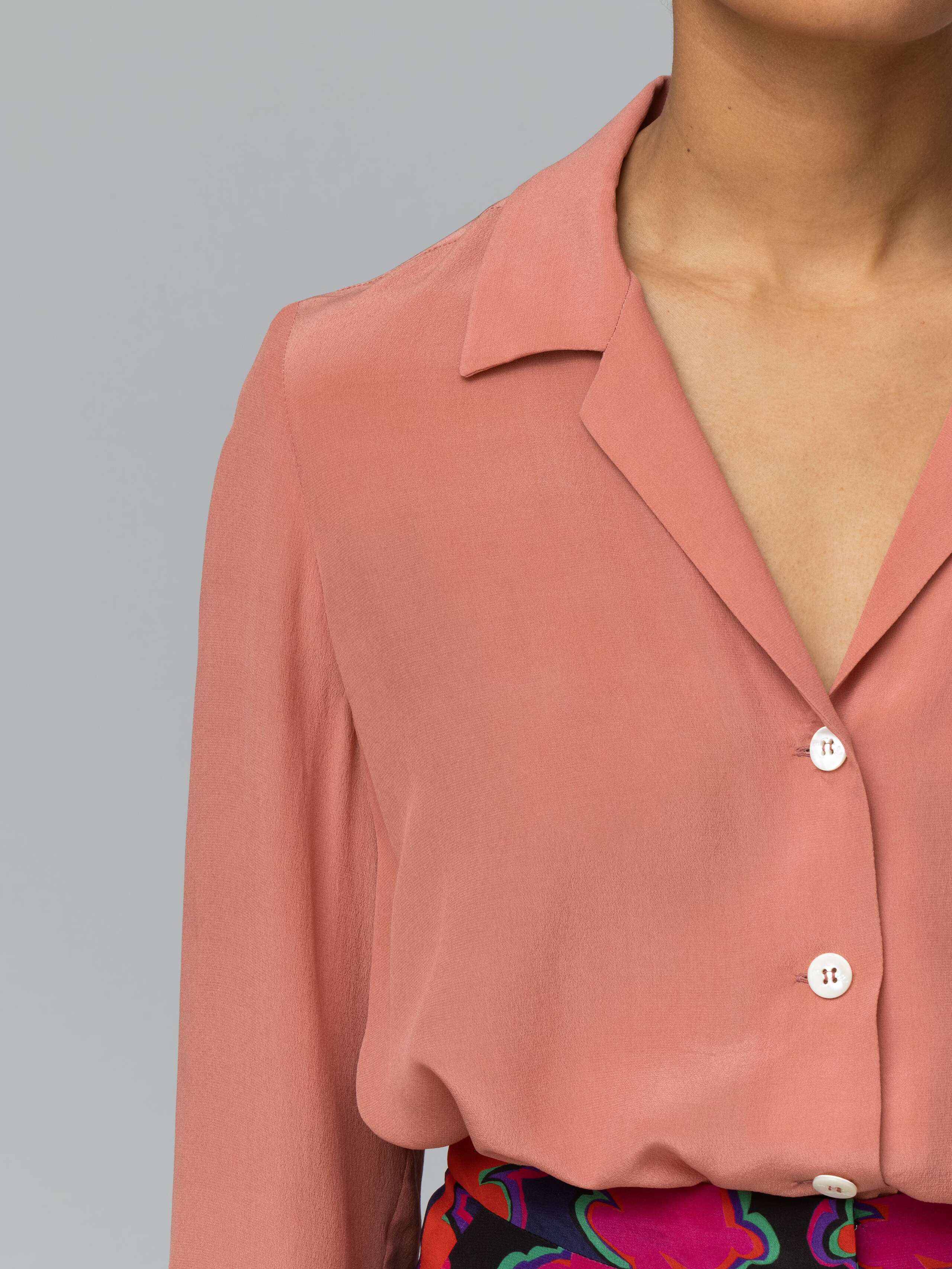 Detail of a long terracotta coloured silk blouse 