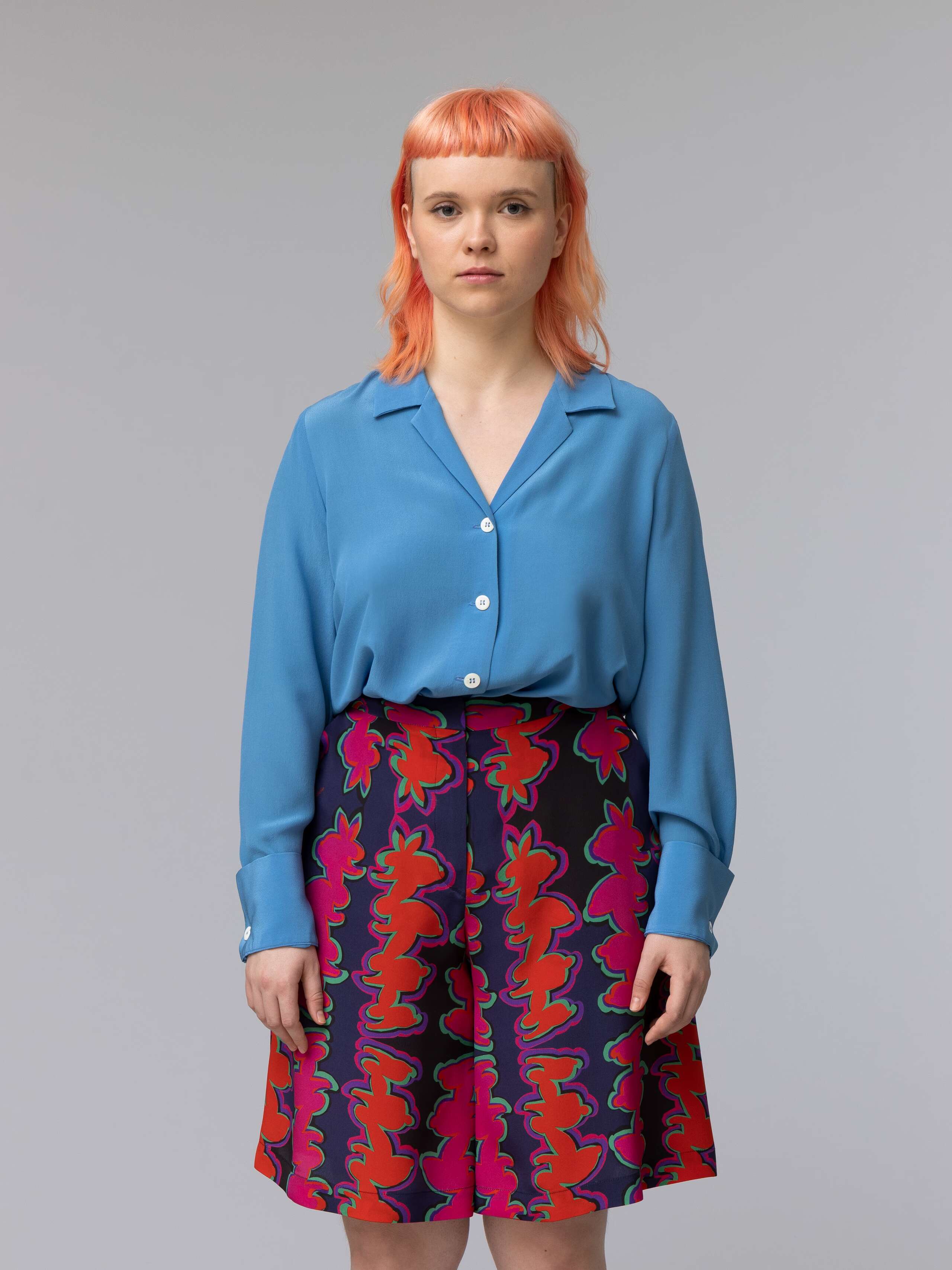 Model wears a blue silk blouse combined with wide summery shorts