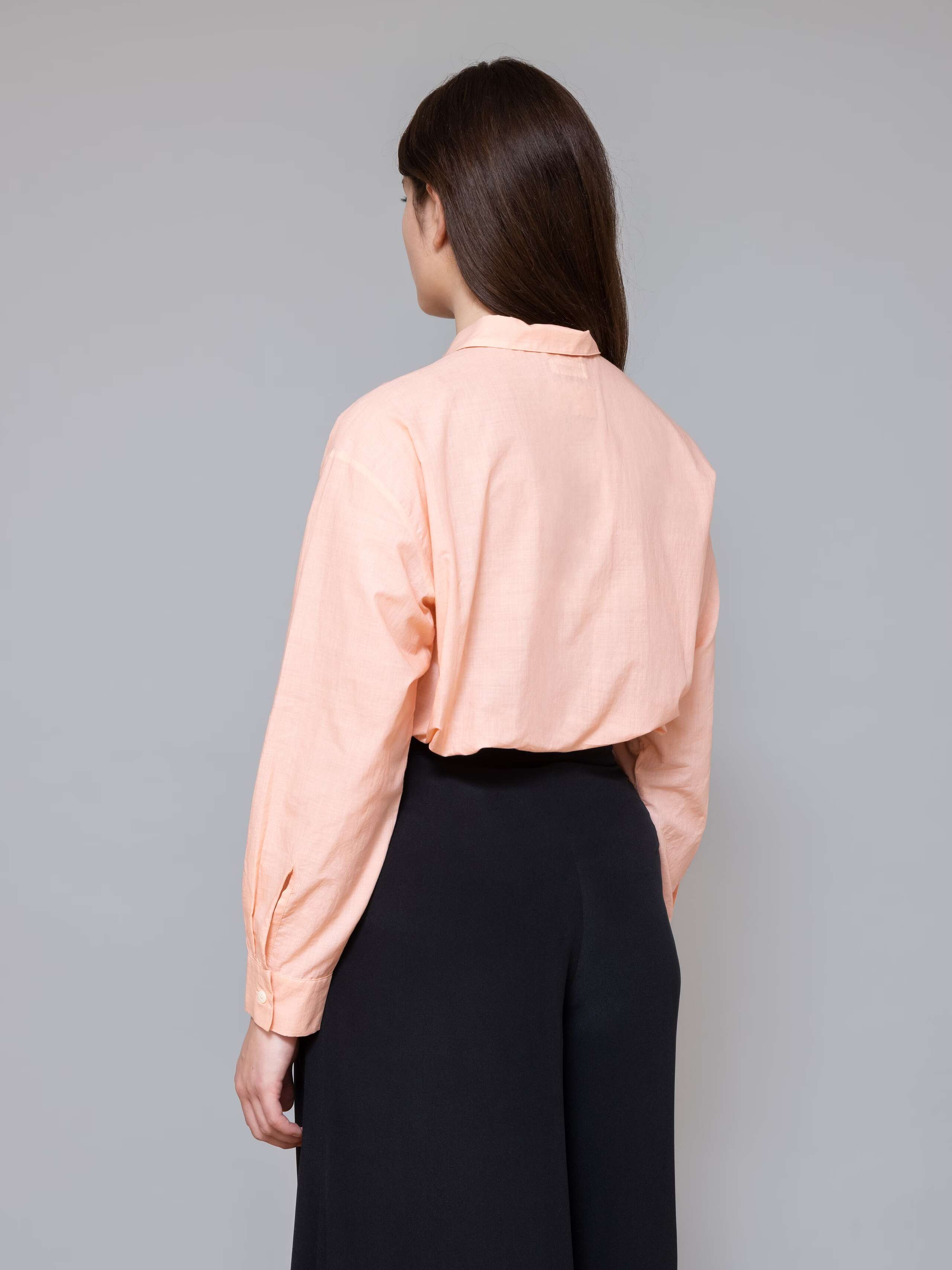 Model is wearing a classic peach coloured blouse made of airy cotton voile