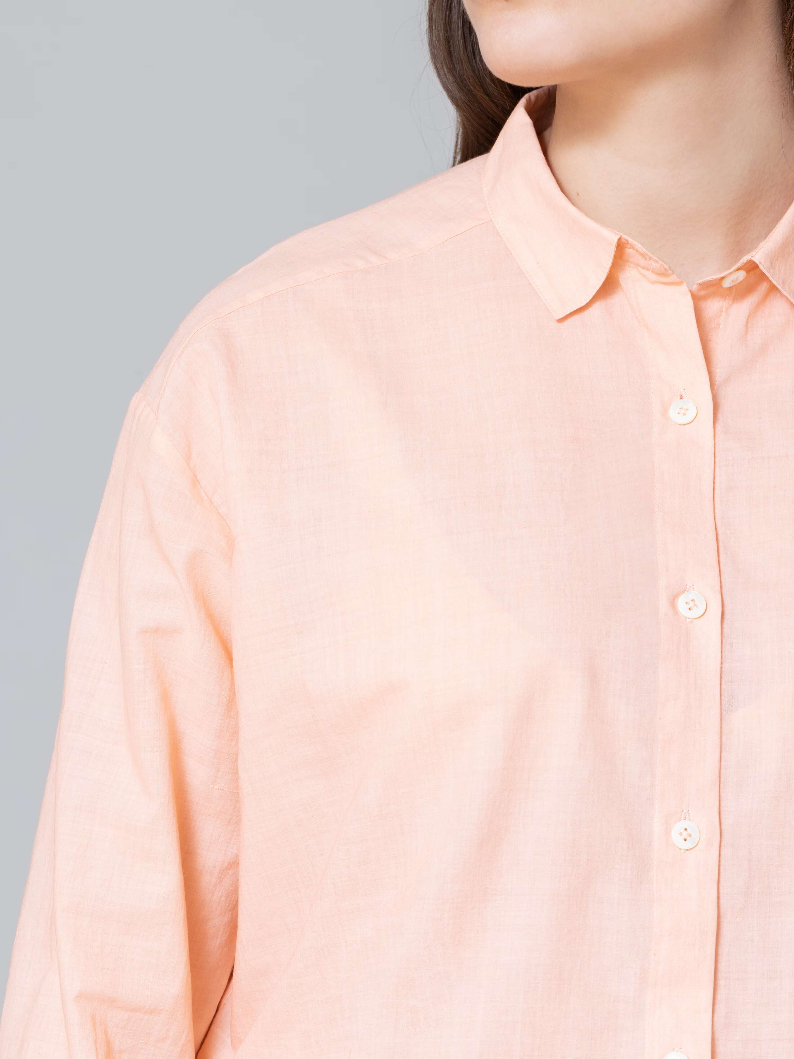 Model is wearing a classic peach coloured blouse made of airy cotton voile
