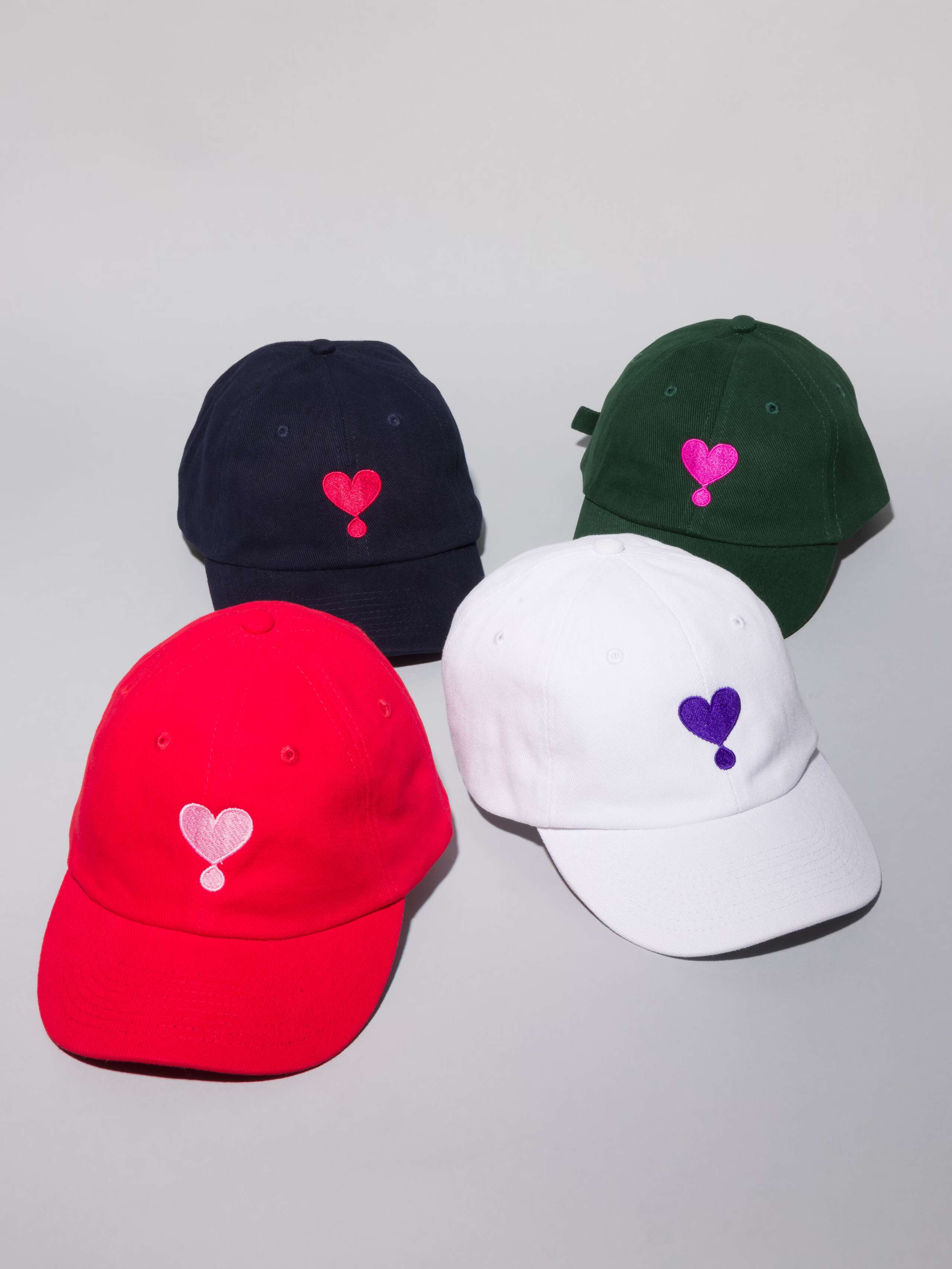 Picture of four base caps in white, dark green, red and navy with heart embroidery