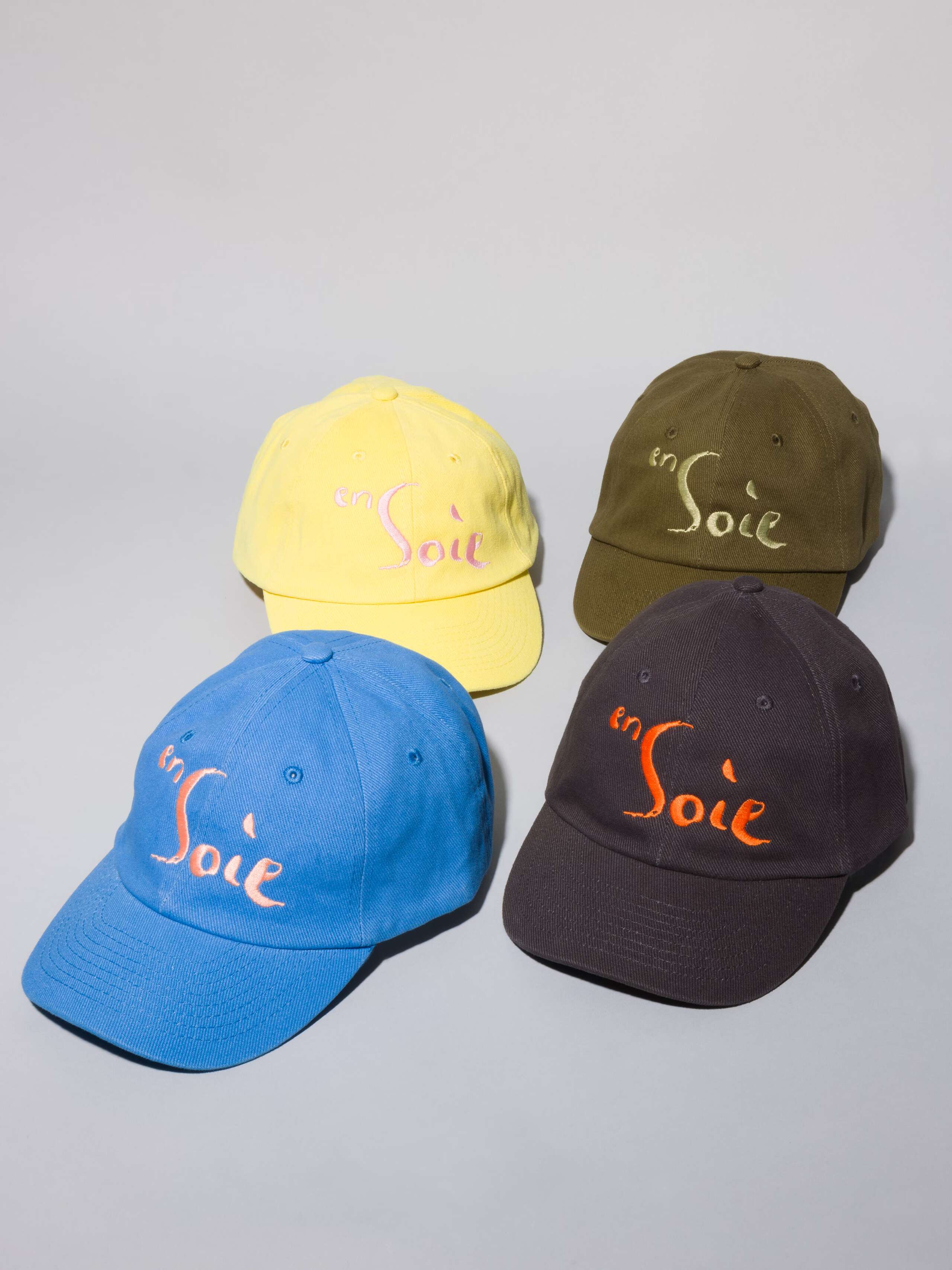 Picture of four base capsin blue, yellow, olive and grey with enSoie embroidery