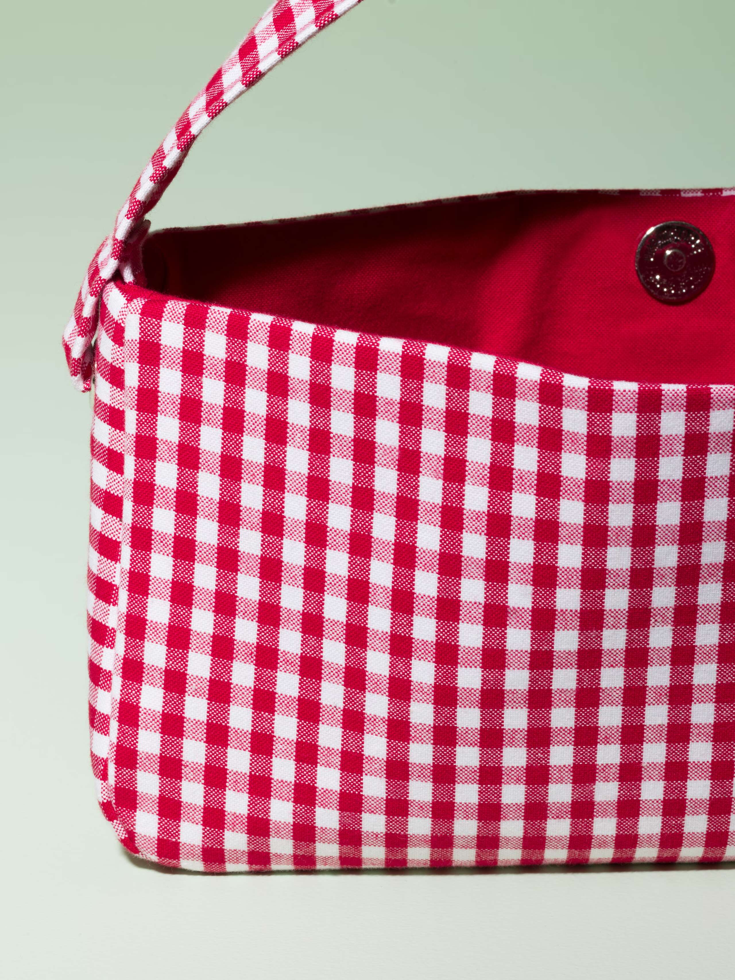 Detail of a cute baguette bag made of cotton featuring a red vichy check pattern