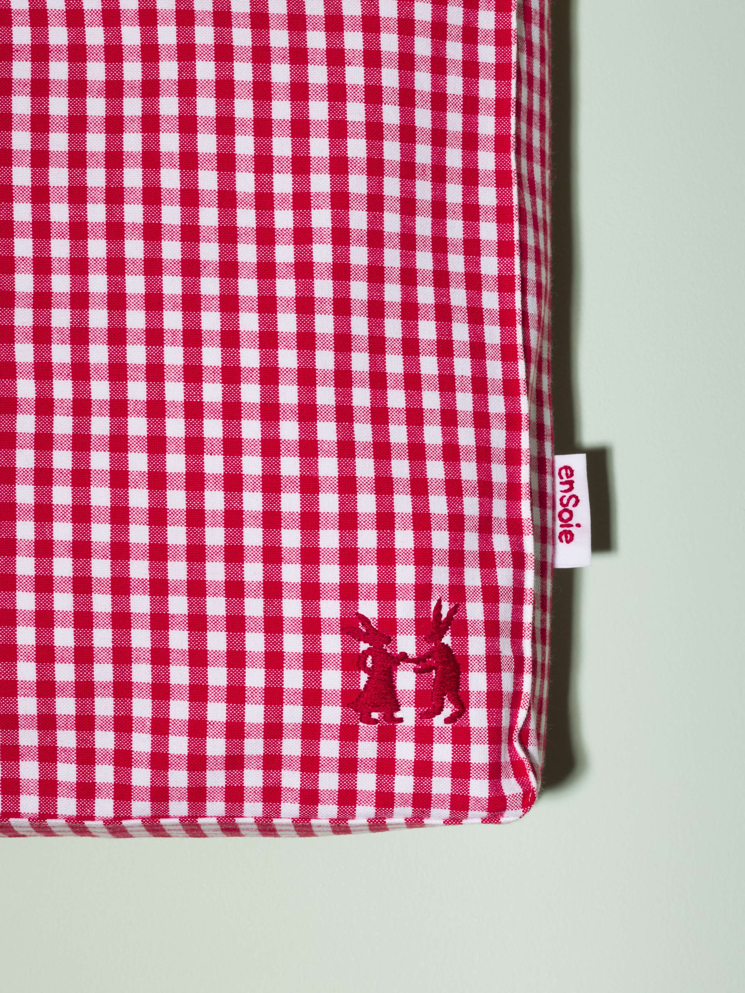 Picture of a detail of a small cotton bag featuring a red vichy check pattern
