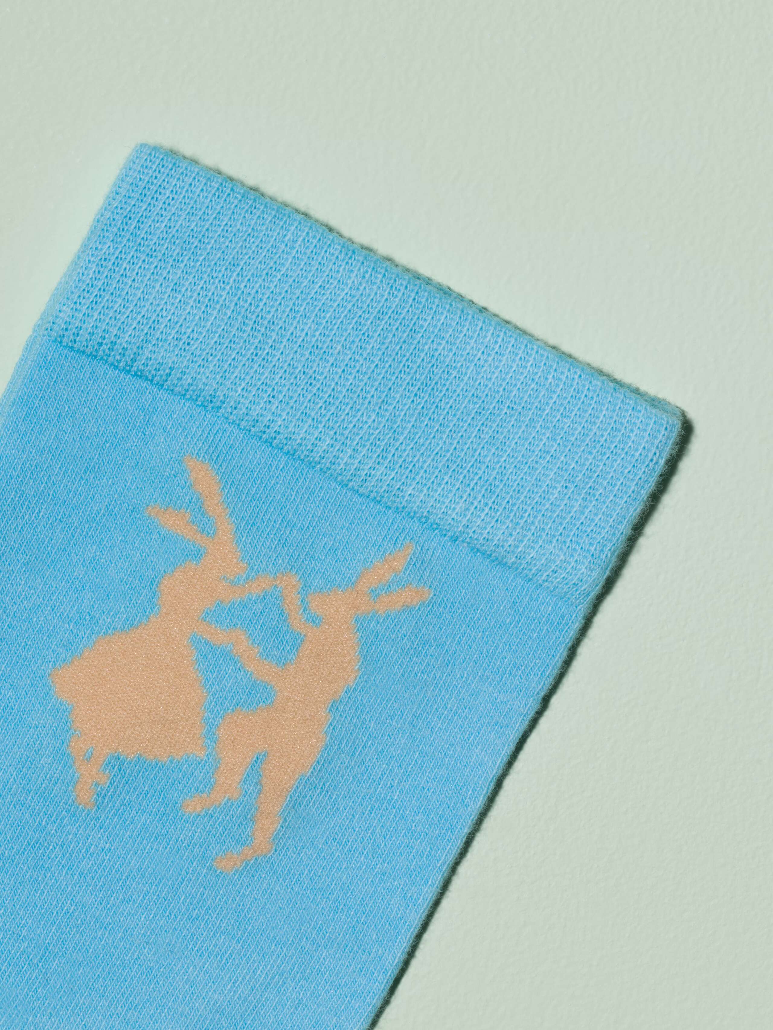 Picture of a blue sock with beige rabbit