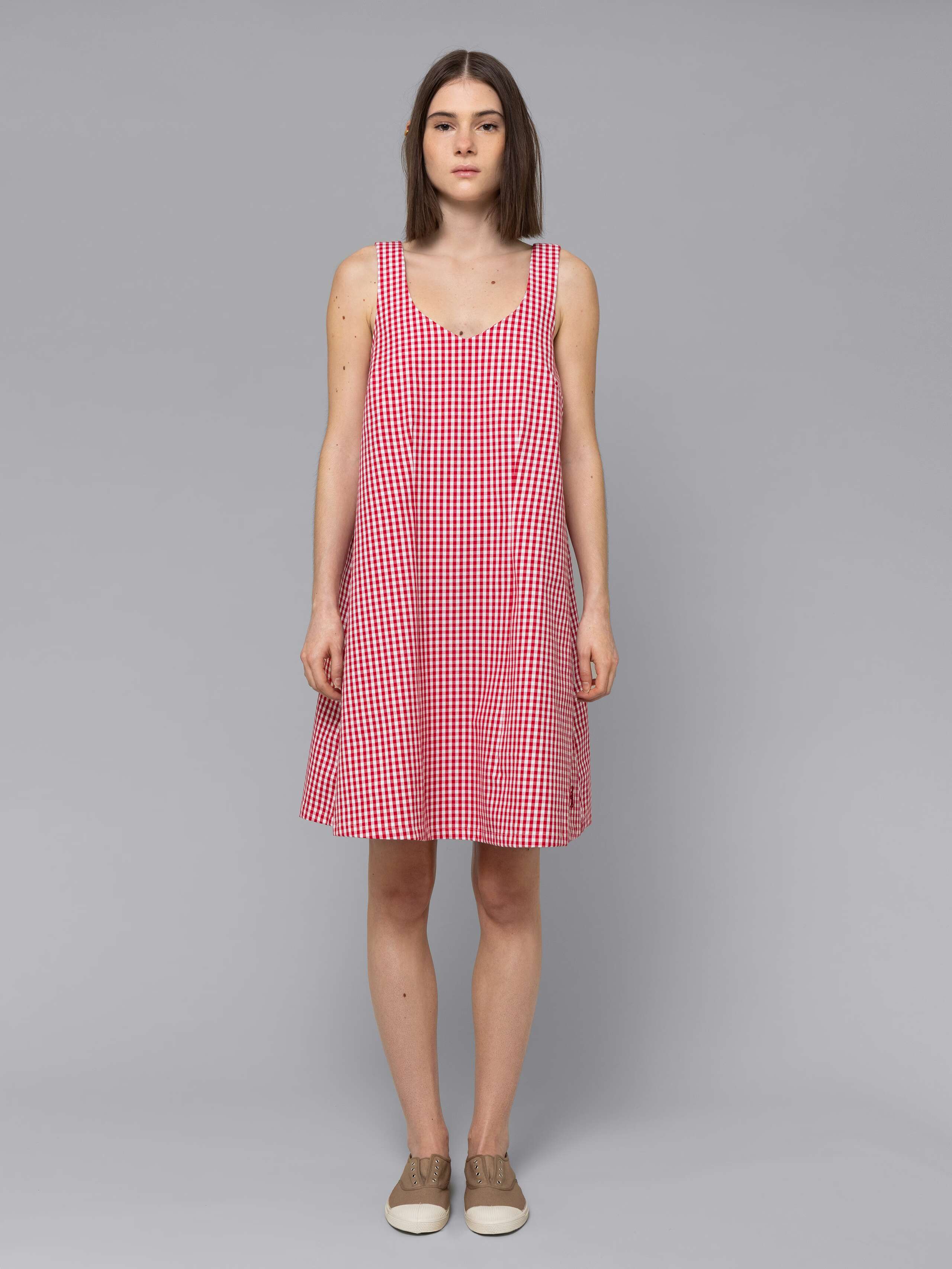 Female model is wearing an airy cotton dress featuring a red vichy check pattern