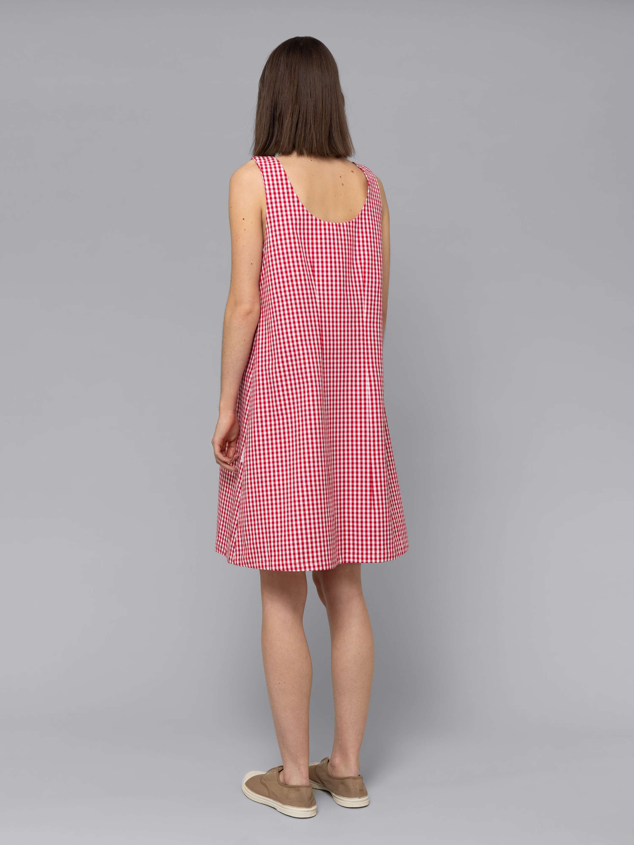 Female model is wearing an airy cotton dress featuring a red vichy check pattern