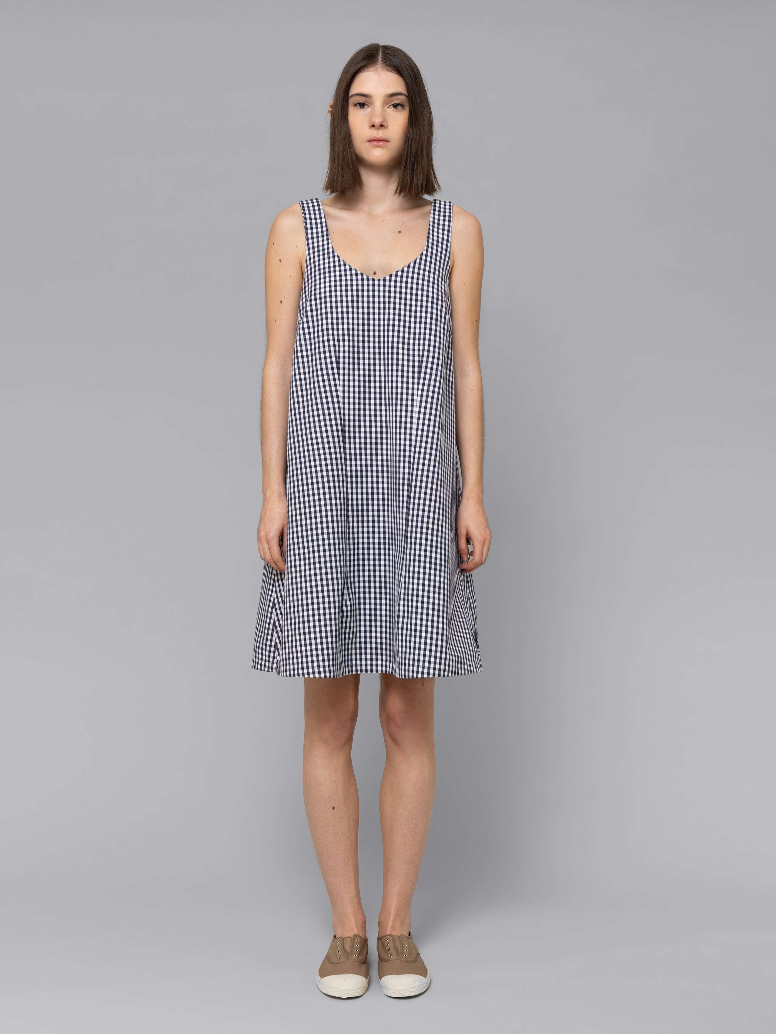 Female model is wearing an airy cotton dress featuring a navy vichy check pattern