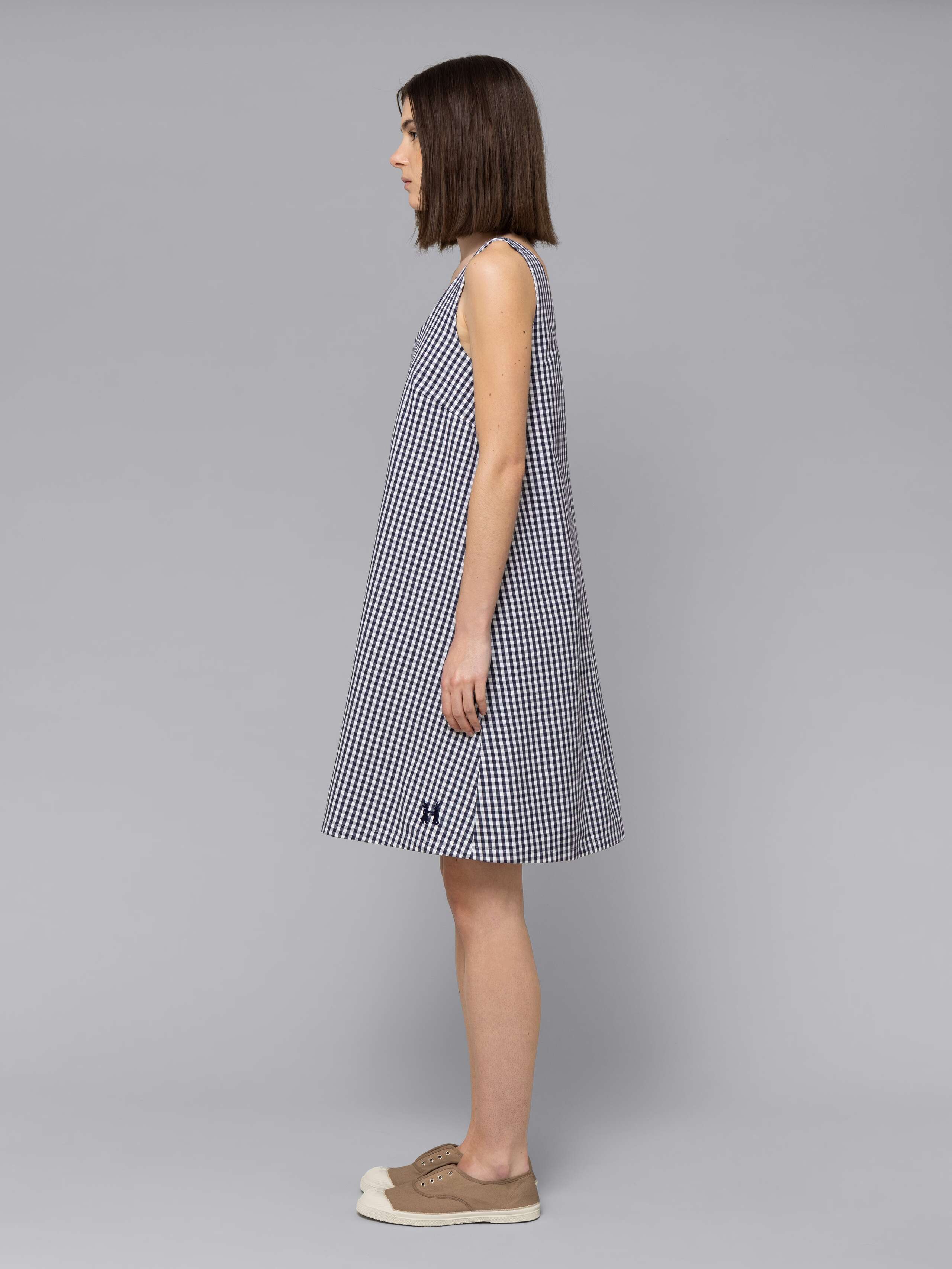 Female model is wearing an airy cotton dress featuring a navy vichy check pattern