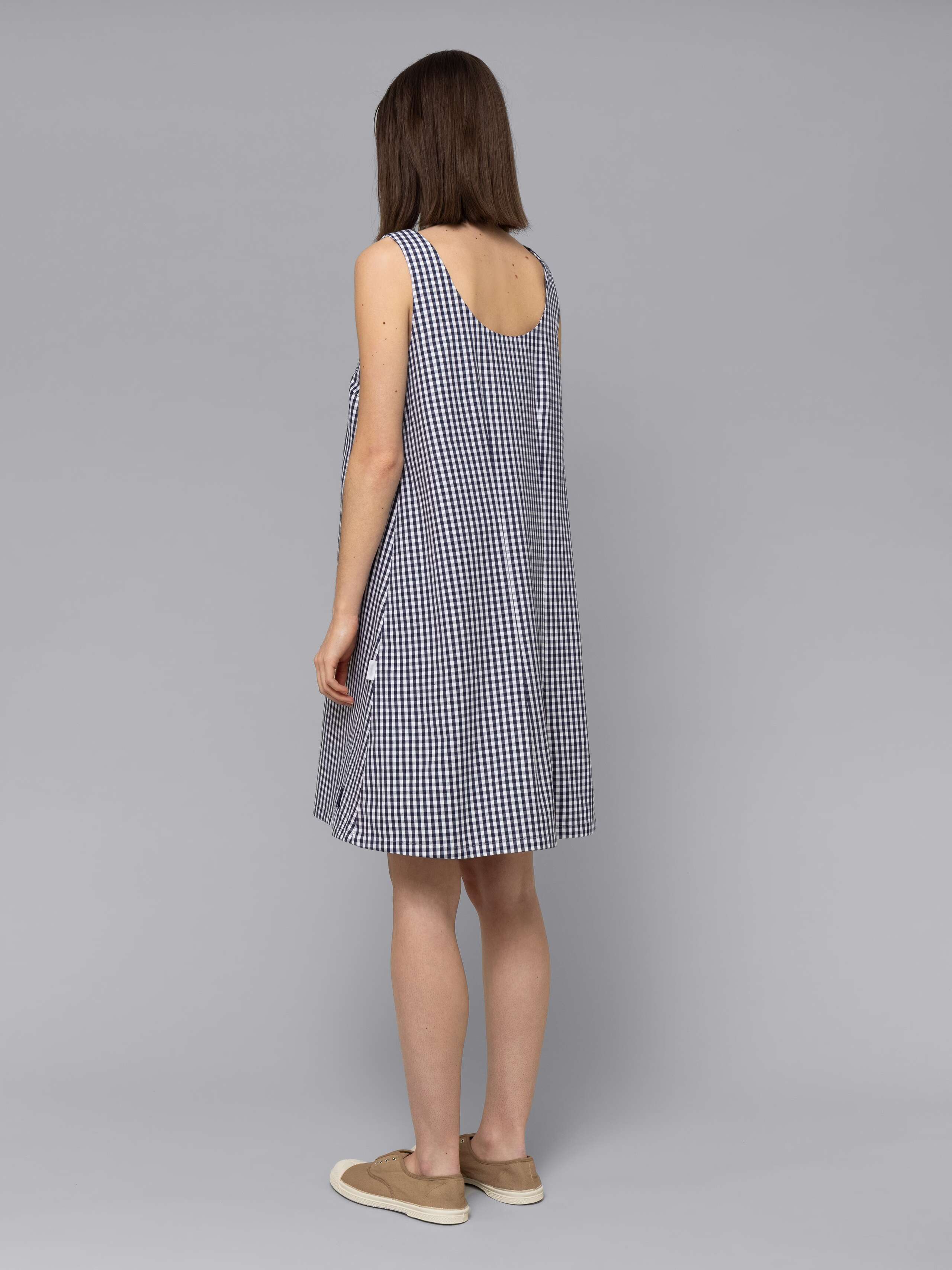 Female model is wearing an airy cotton dress featuring a navy vichy check pattern