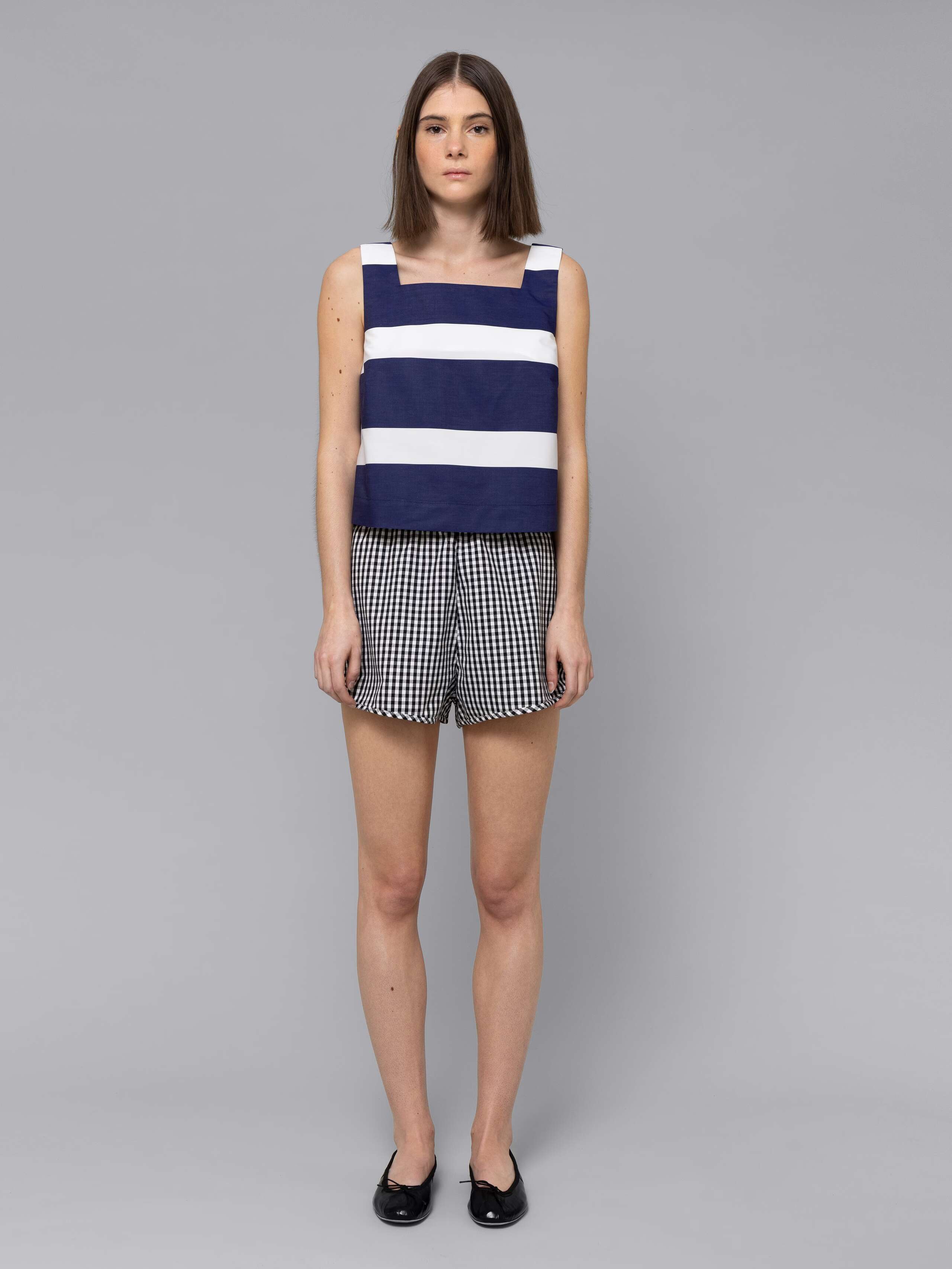 Female model is wearing a sporty cotton short in a black vichy check pattern