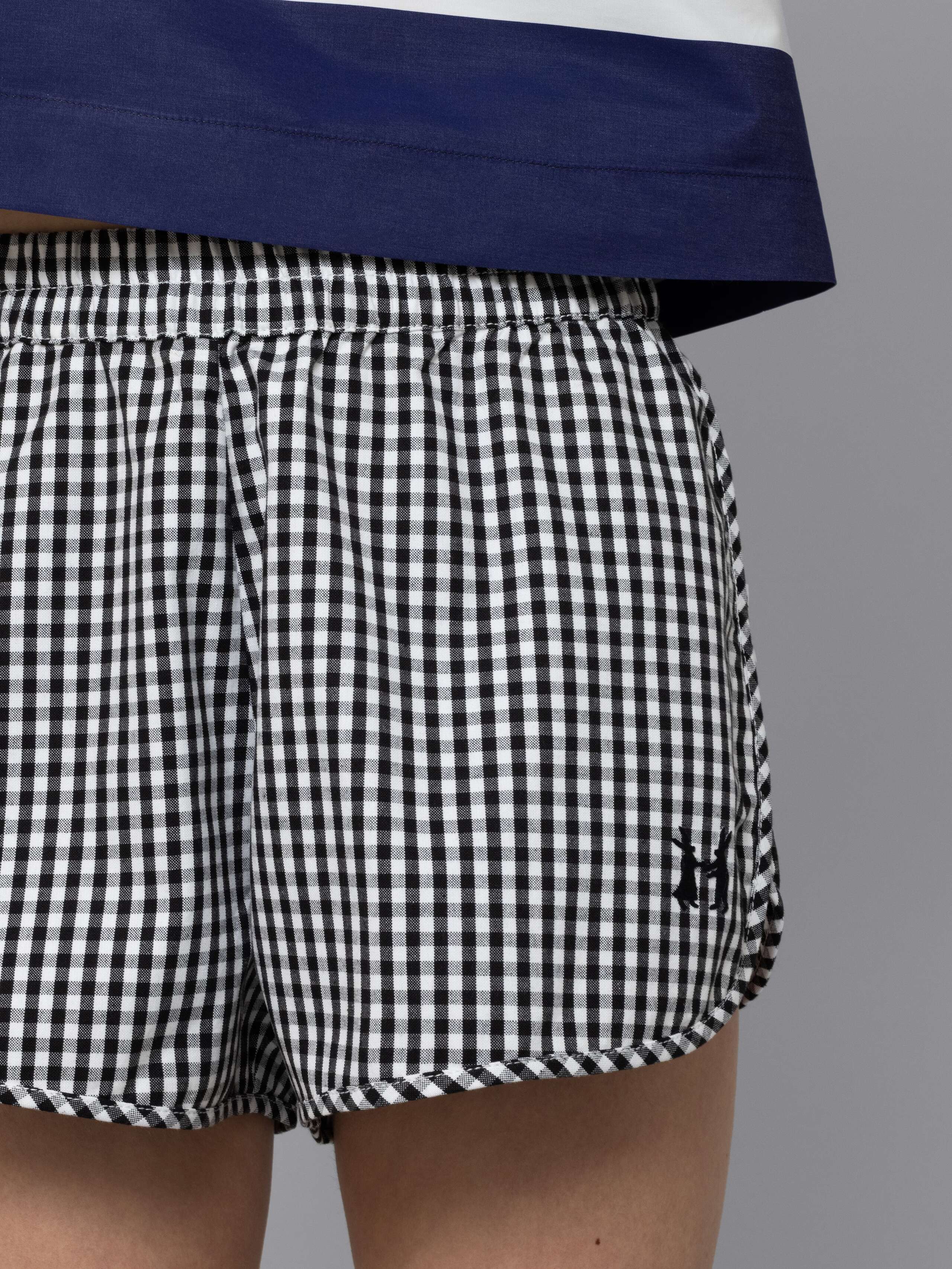 Female model is wearing a sporty cotton short featuring a black vichy check pattern