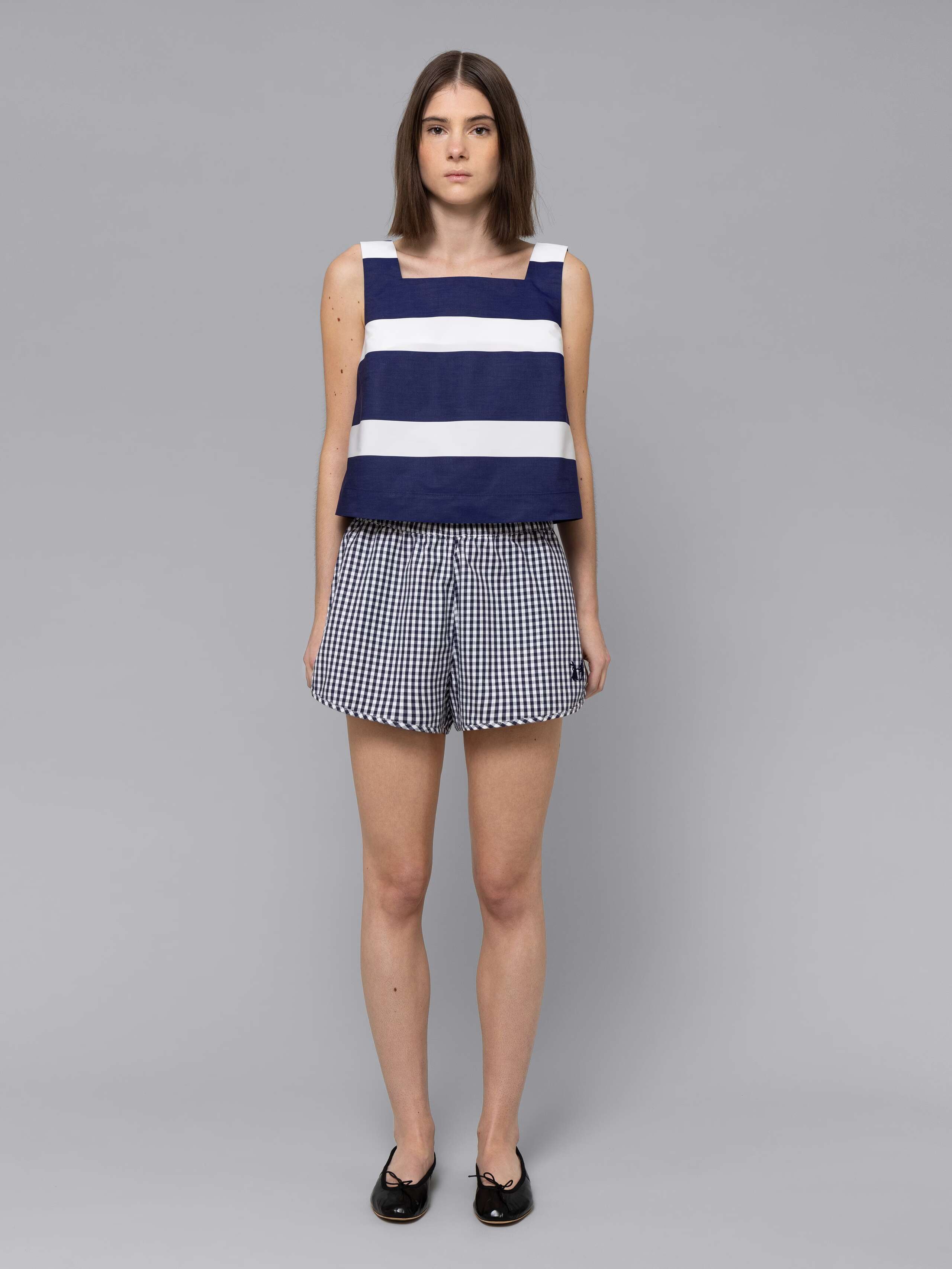 Female model is wearing a sporty cotton short in a navy vichy check pattern