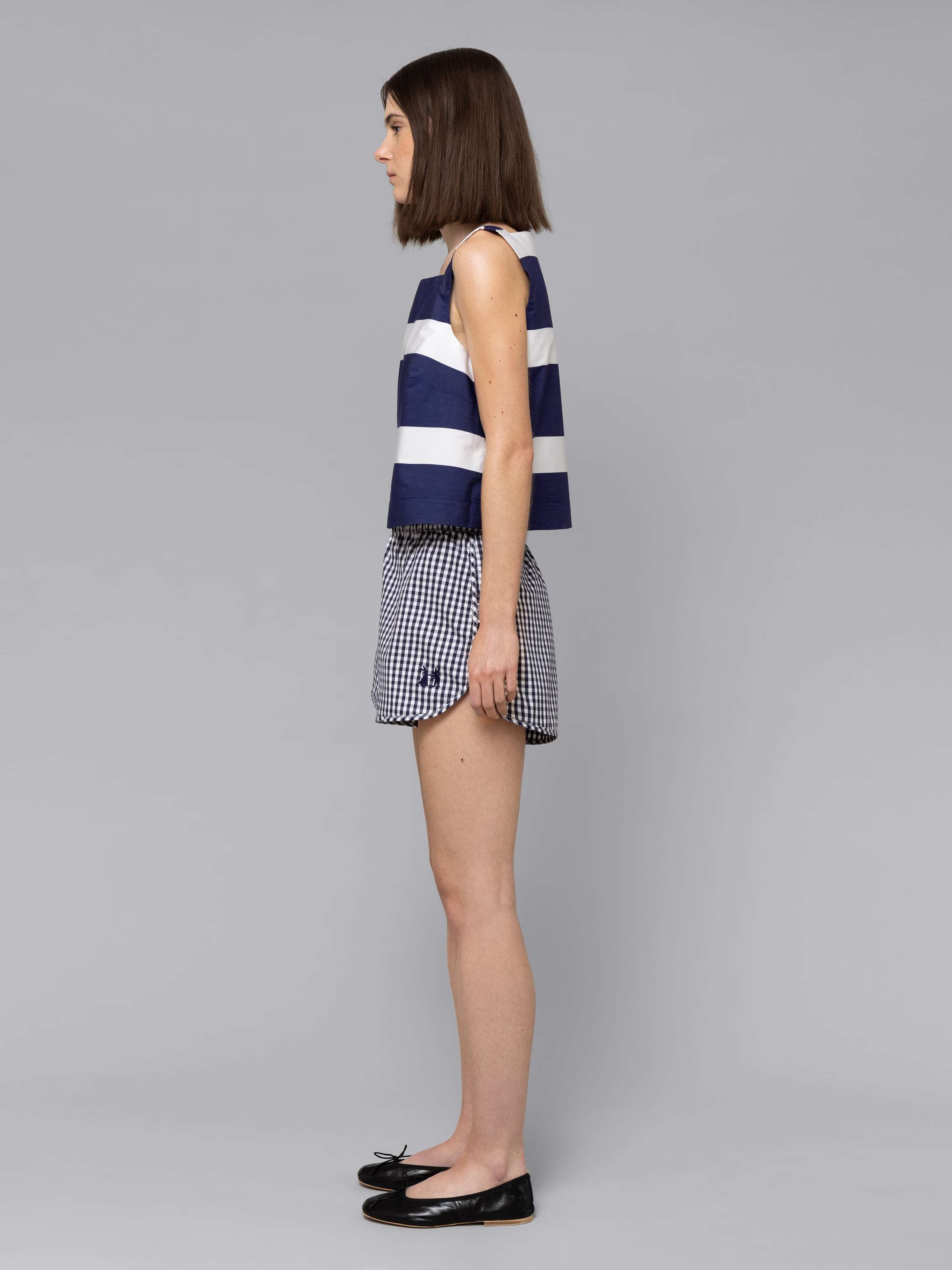 Female model is wearing a sporty cotton short in a navy vichy check pattern