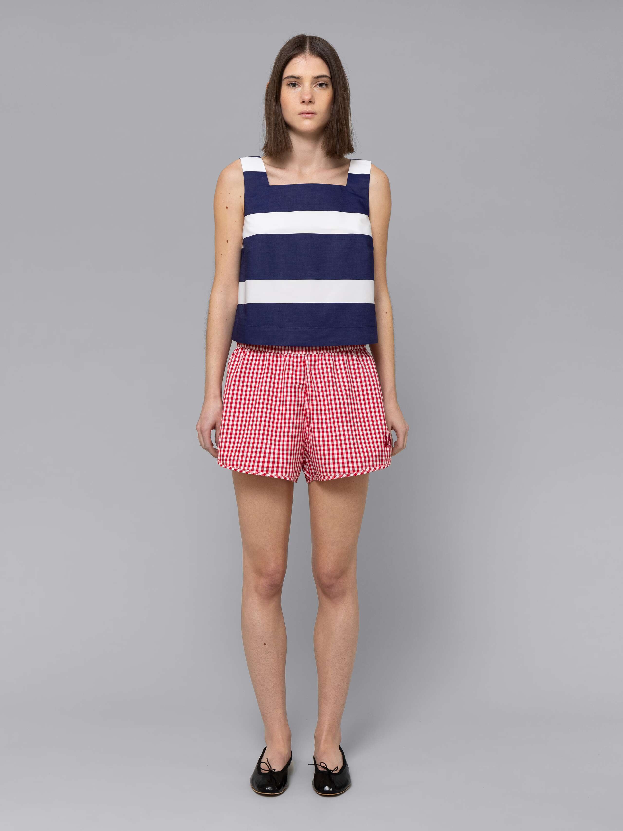 Female model is wearing a sporty cotton short featuring a red vichy check pattern