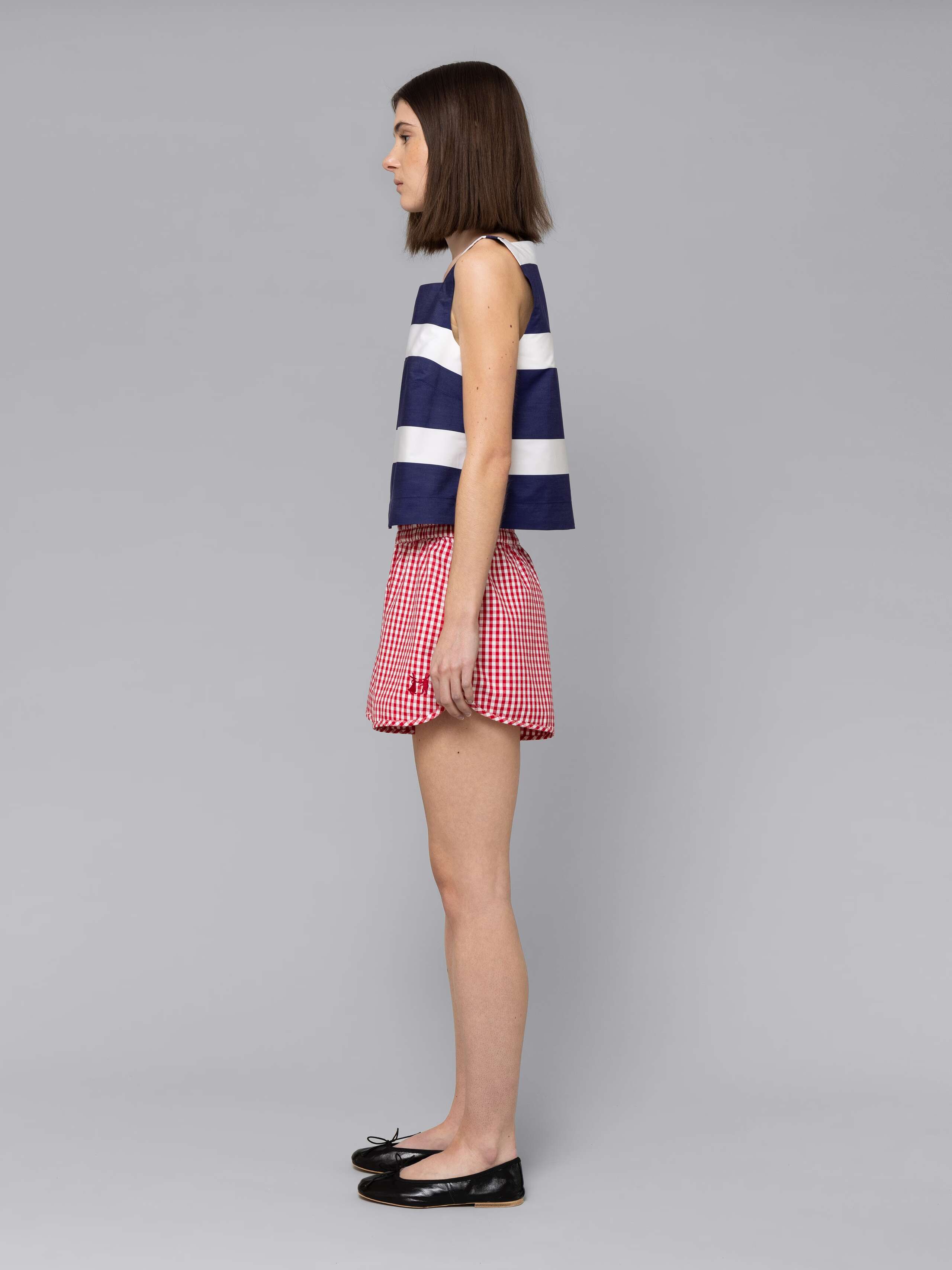 Female model is wearing a sporty cotton short featuring a red vichy check pattern