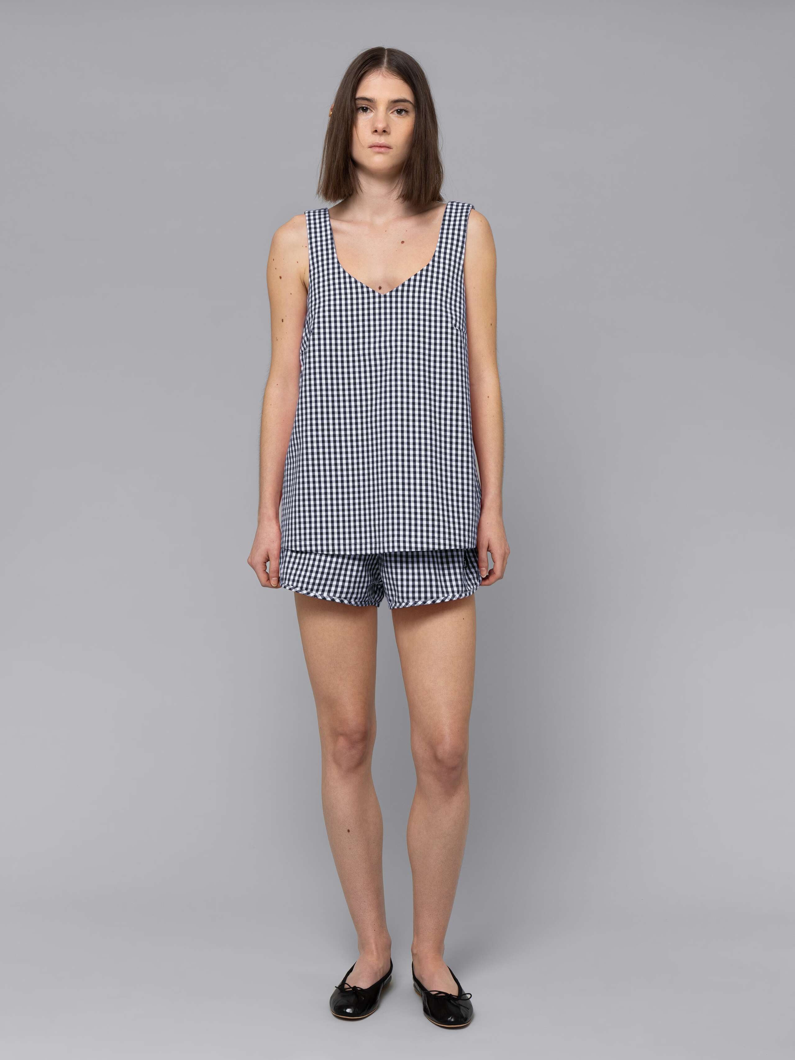 Female model is wearing a combination of a long airy cotton top and a sporty cotton short featuring a beautiful navy vichy check pattern