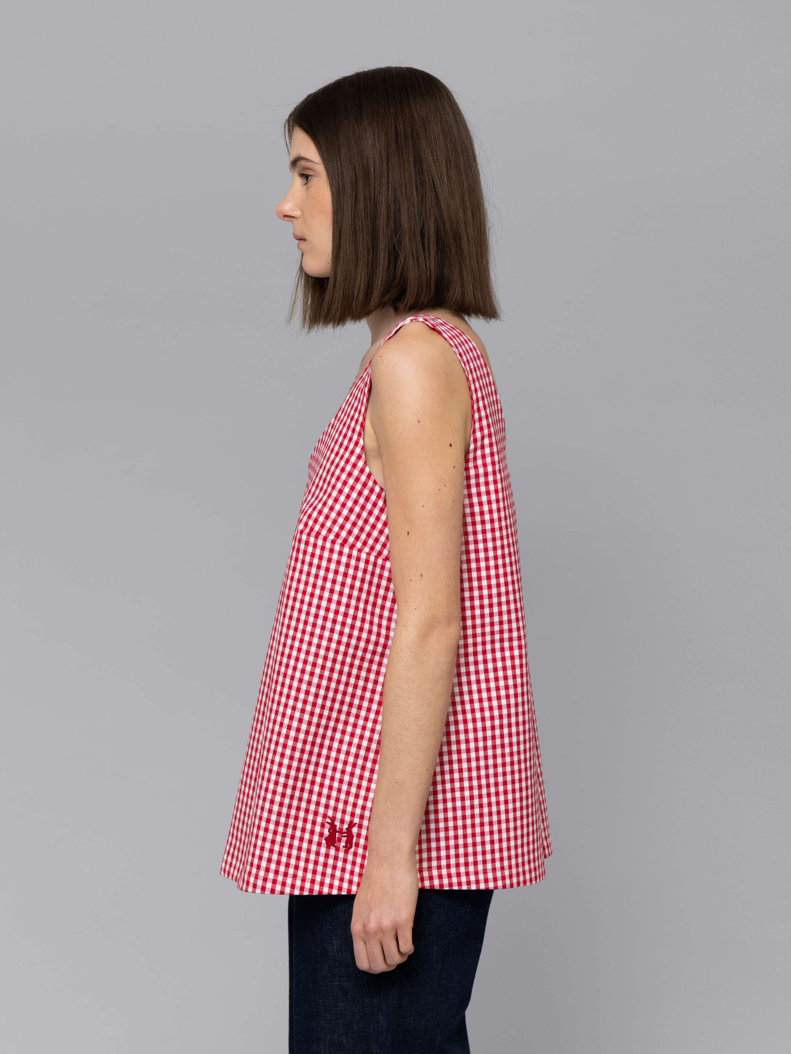 Female model is wearing a an airy long top featuring a beautiful red vichy check pattern
