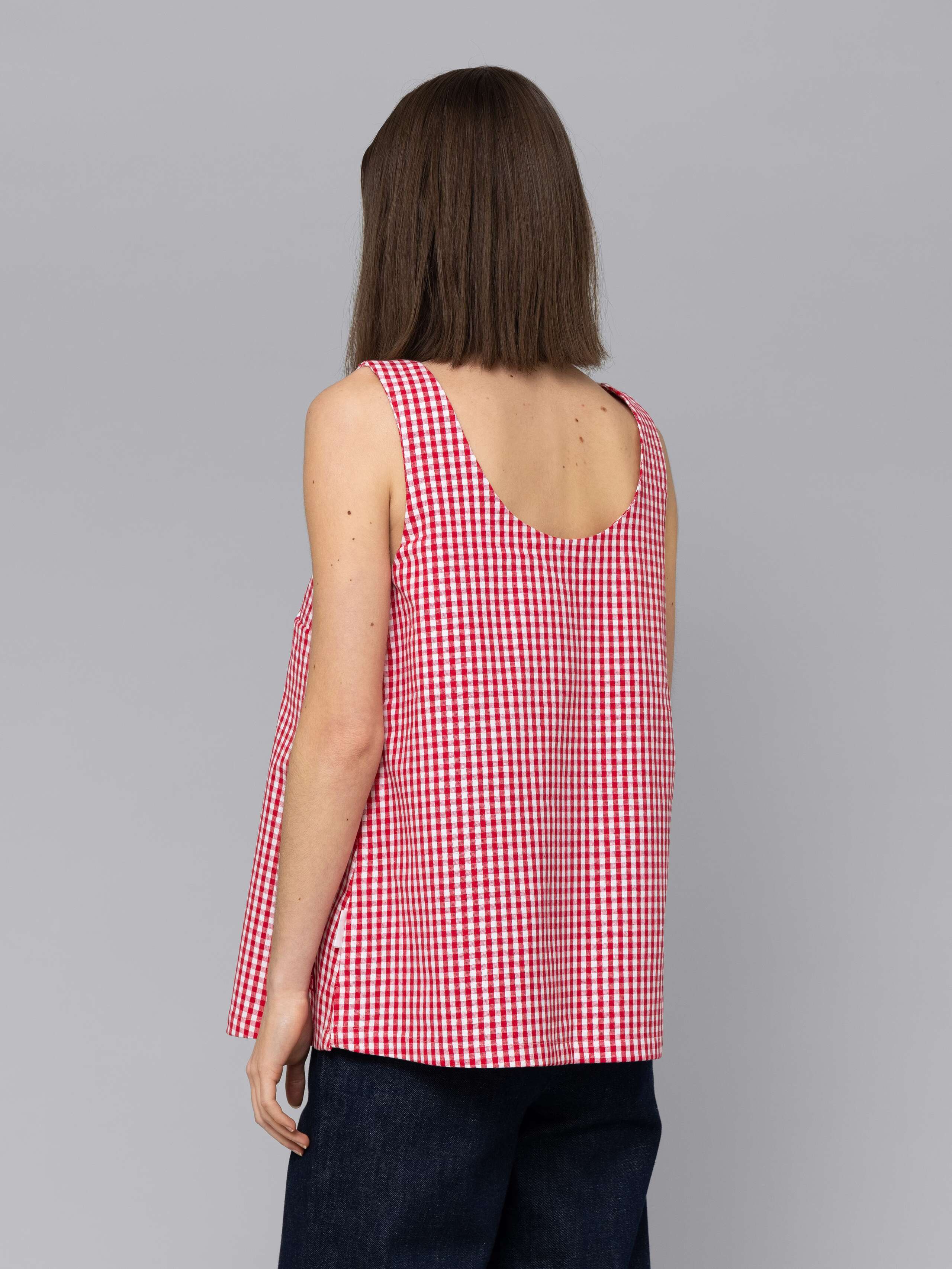 Female model is wearing a an airy long top featuring a beautiful red vichy check pattern