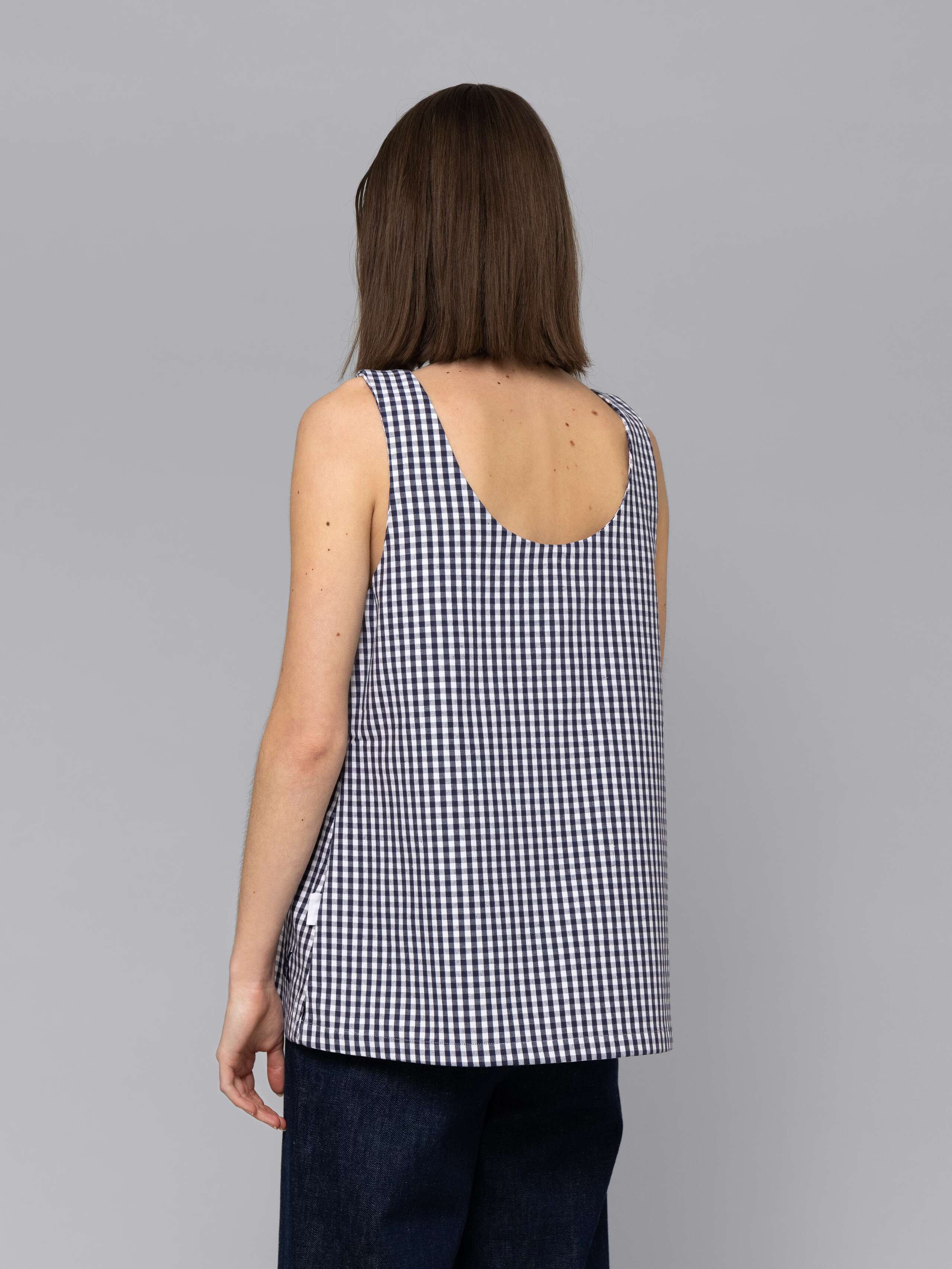 Female model is wearing a an airy long top featuring a beautiful navy vichy check pattern