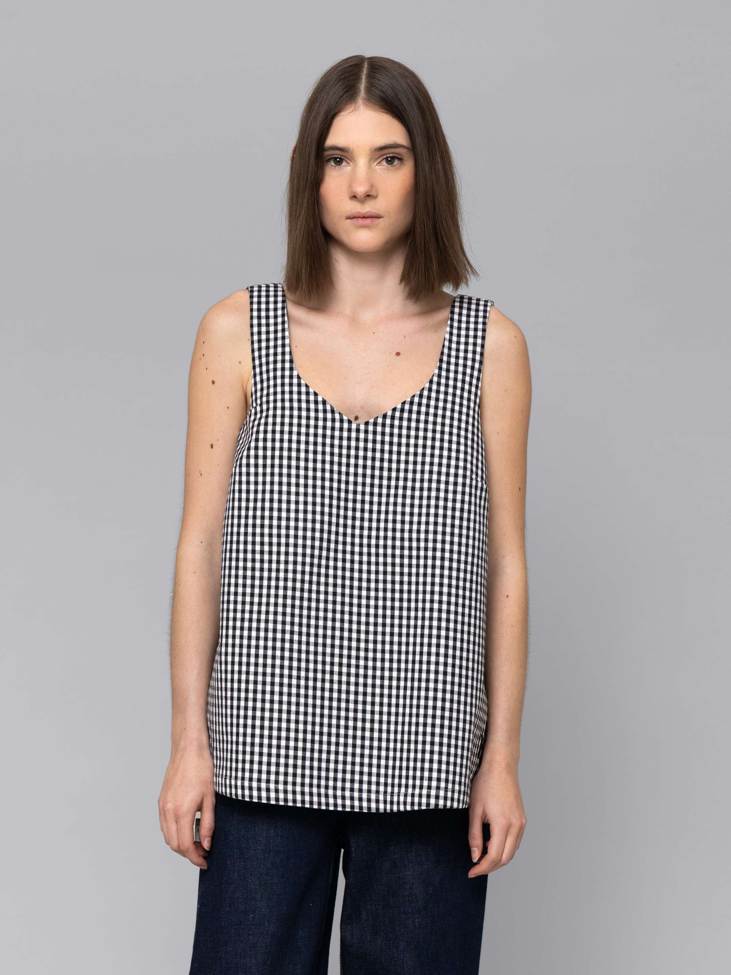 Female model is wearing a an airy long top featuring a beautiful black vichy check pattern