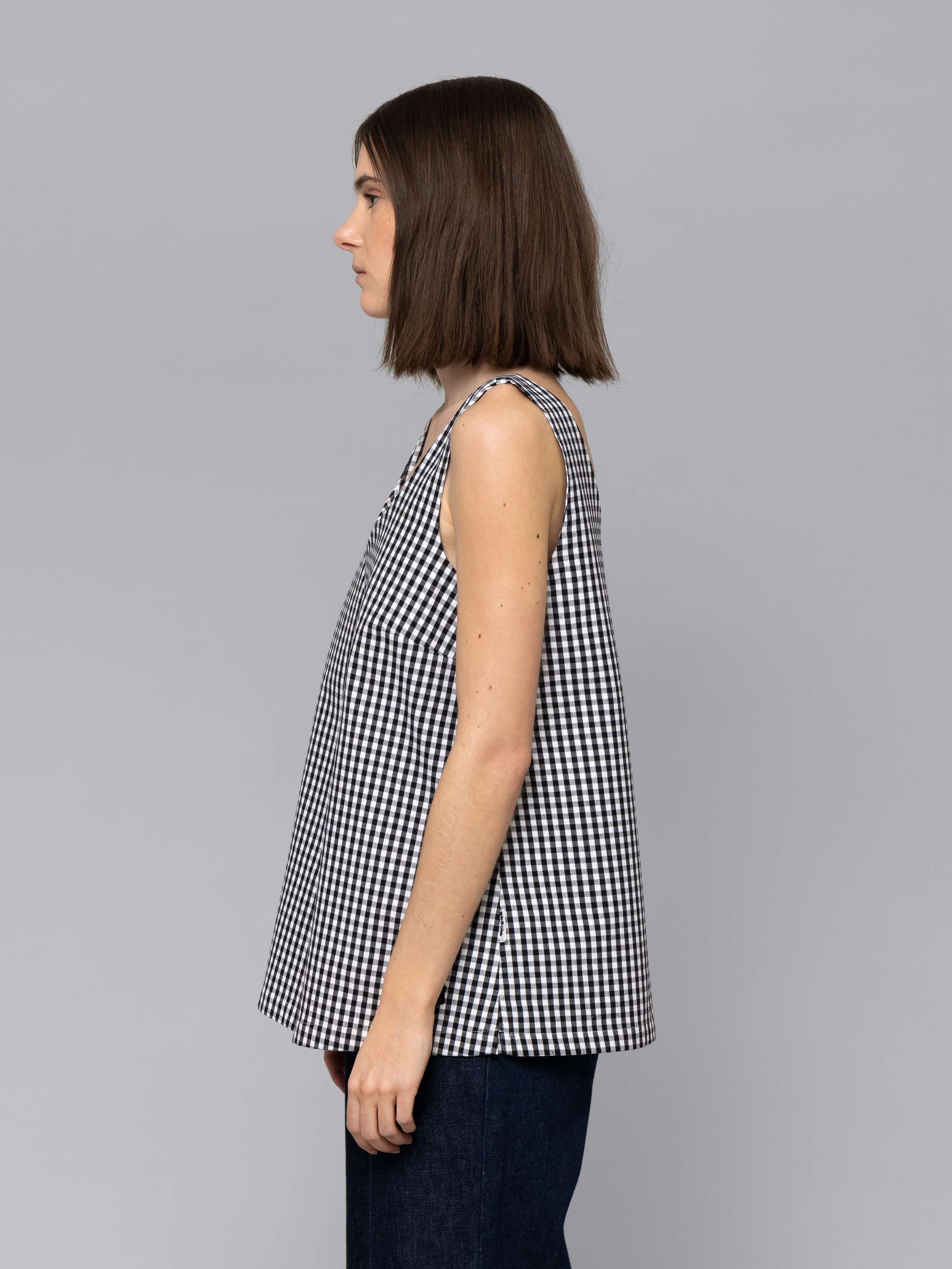 Female model is wearing a an airy long top featuring a beautiful black vichy check pattern