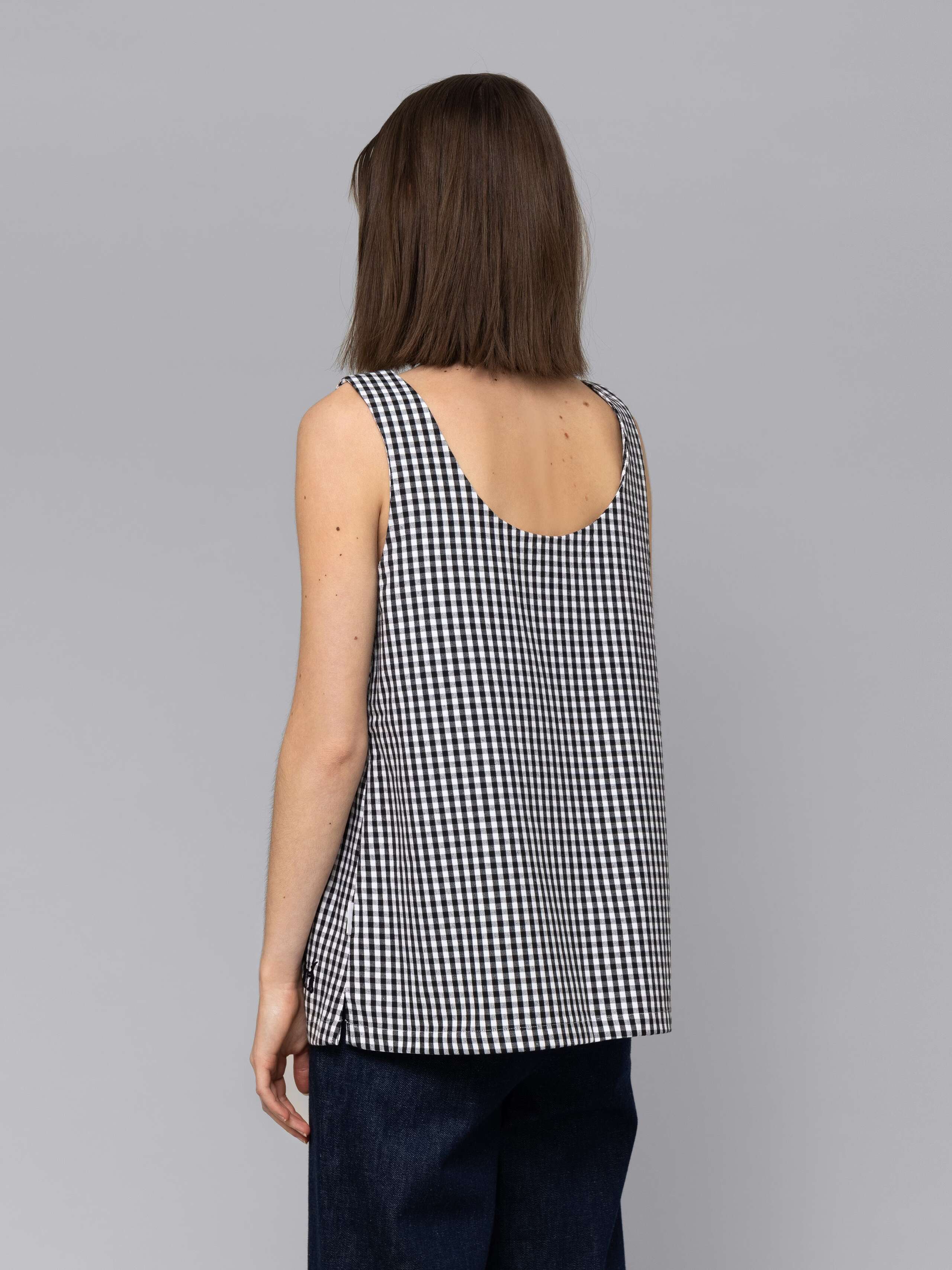 Female model is wearing a an airy long top featuring a beautiful black vichy check pattern