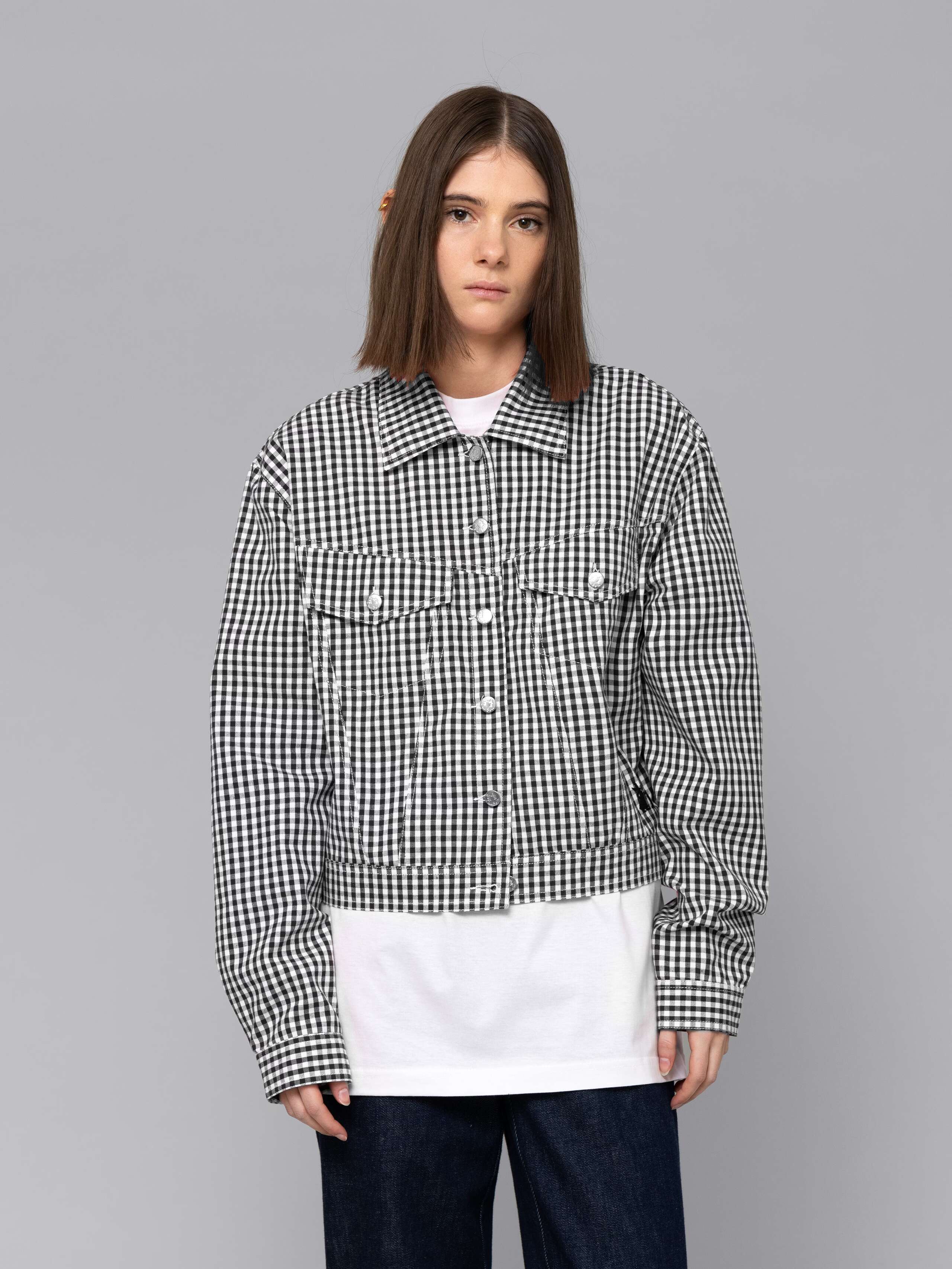 Female model is wearing a a boxy denim trucker jacket featuring a beautiful black vichy check pattern
