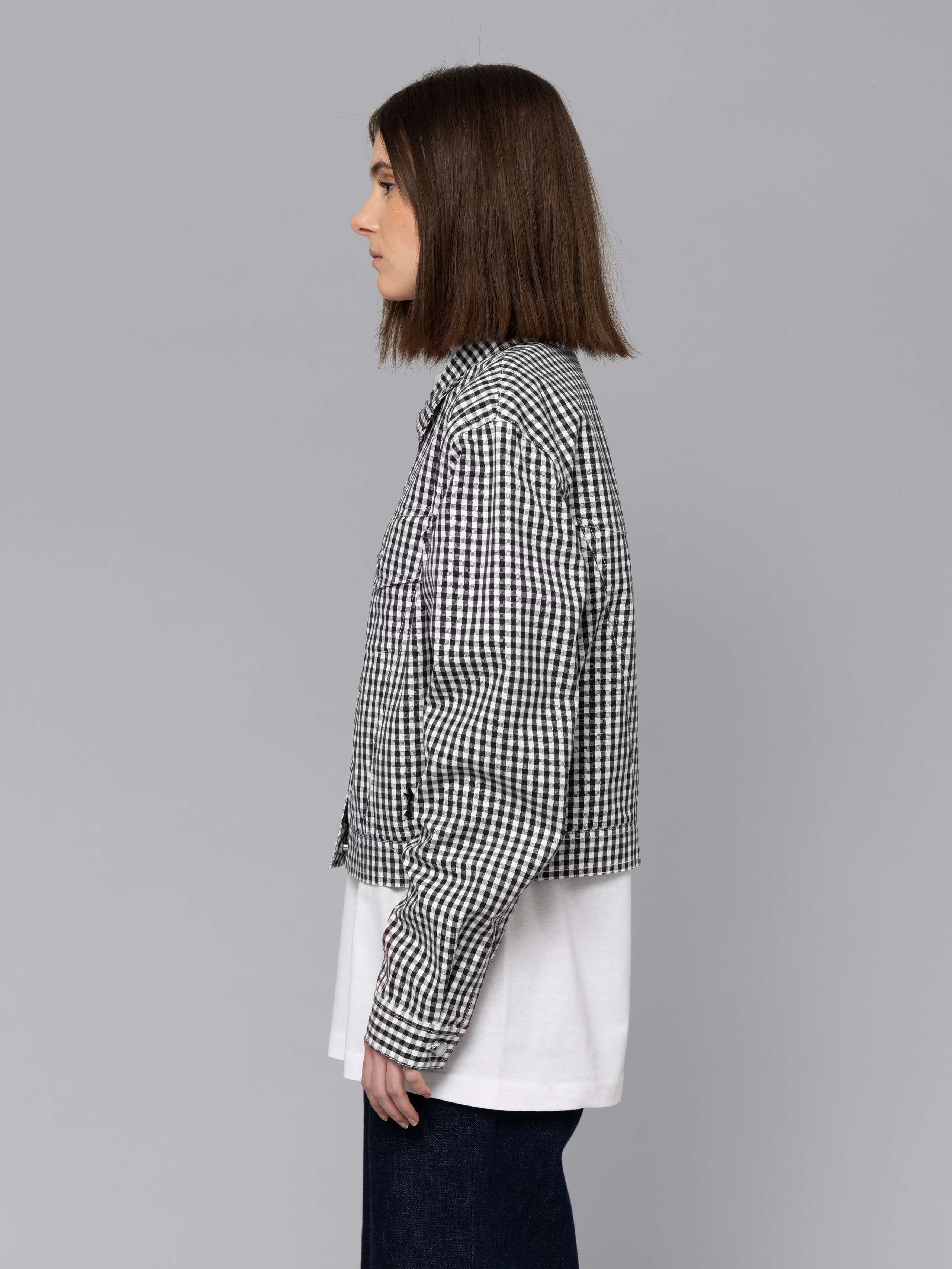 Female model is wearing a a boxy denim trucker jacket featuring a beautiful black vichy check pattern
